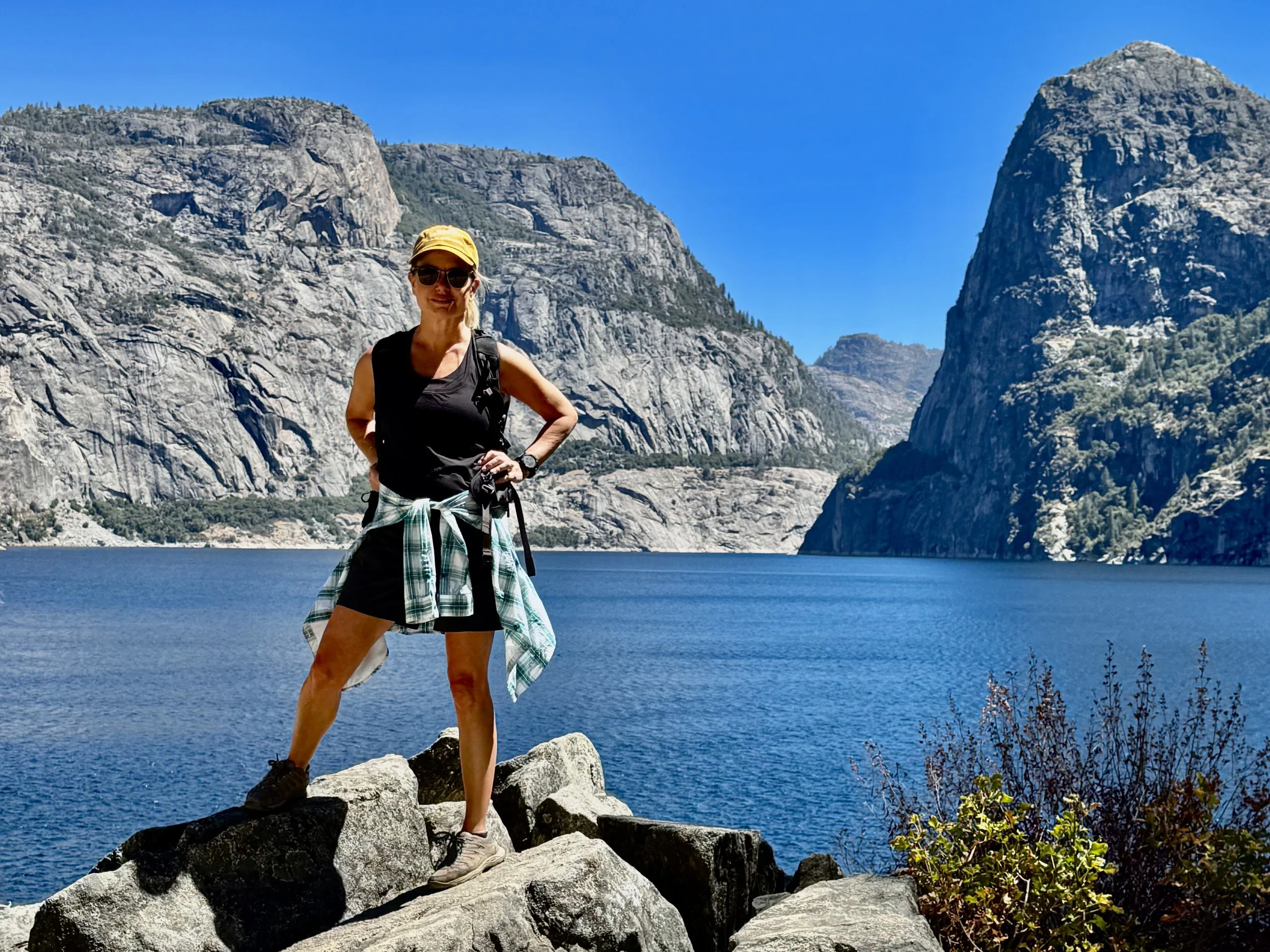 Young woman standing at the water’s edge at Hetch Hetchy Reservoir in Yosemite National Park