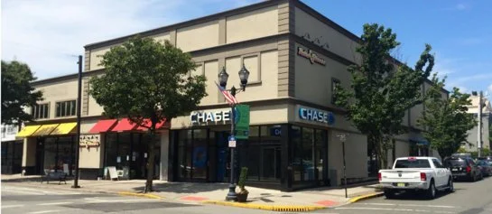 Bayonne retail where you can see Chase bank branch on a city street with trees, parked cars, and a traffic light