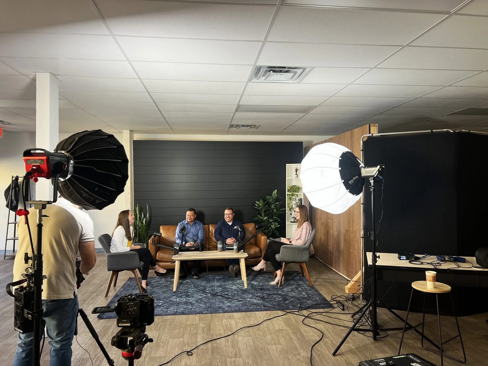 A studio setting with four people participating in a recorded discussion, with professional lighting and camera equipment in view.