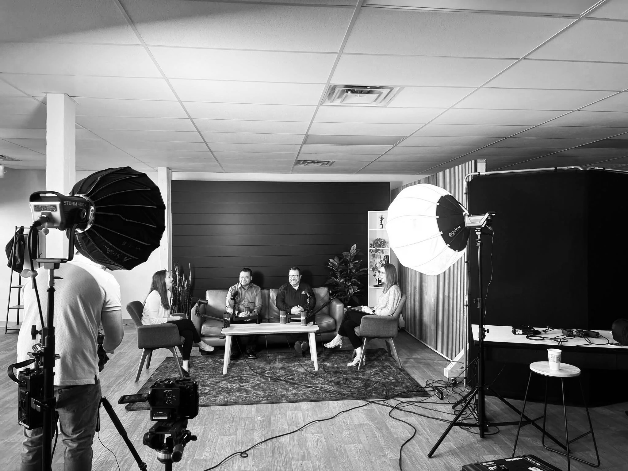 People filming a video or podcast interview in a studio with lighting equipment and cameras