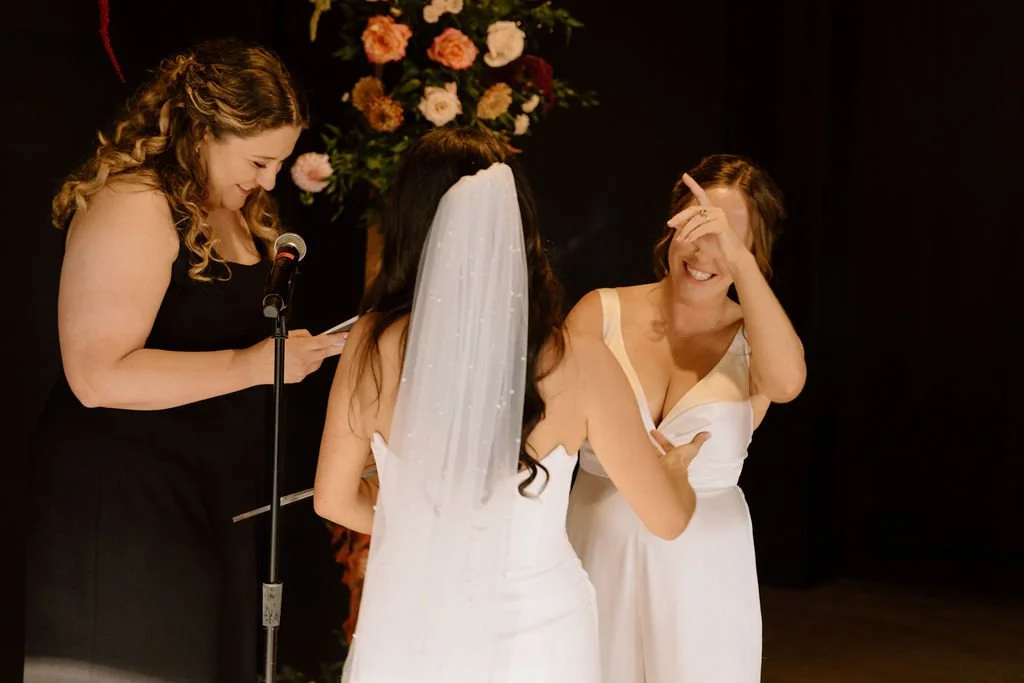 candid moment of brides laughing during their wedding ceremony at the ivy at ellis preserve