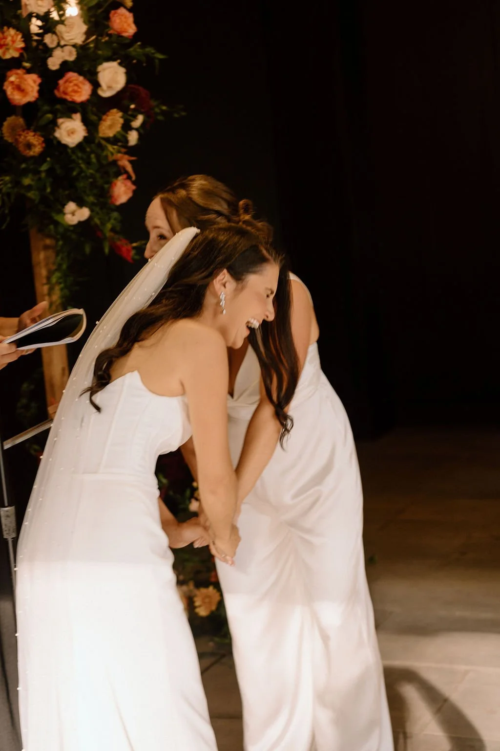 candid moment of brides laughing during their wedding ceremony at the ivy at ellis preserve