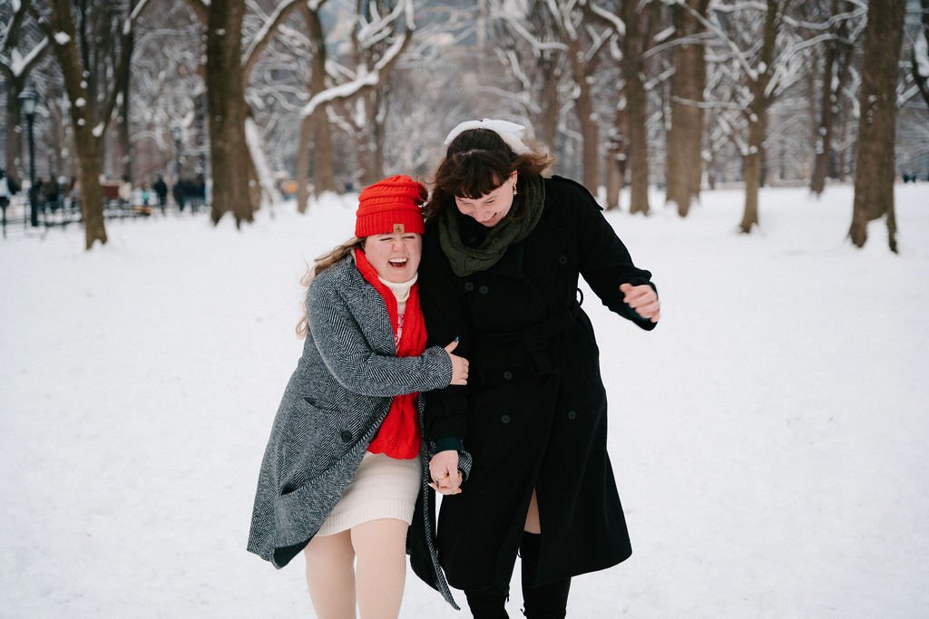 playful lesbian engagement photos in the snow at central park