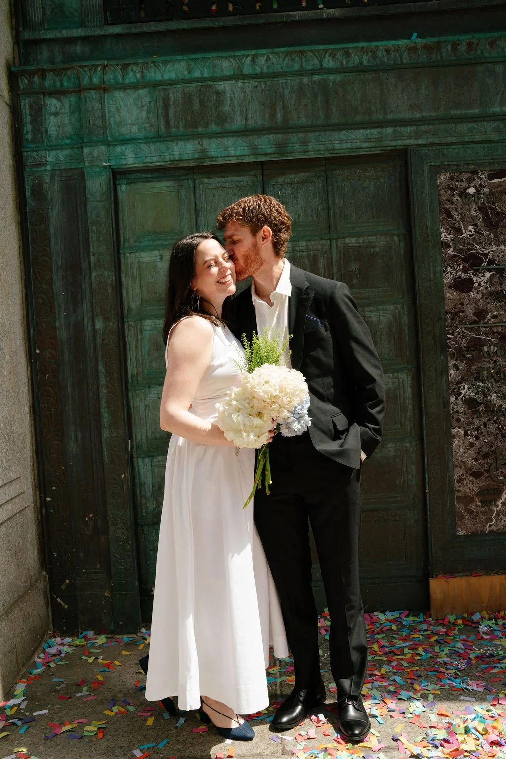 Couple embracing outside New York City Hall after their courthouse wedding.