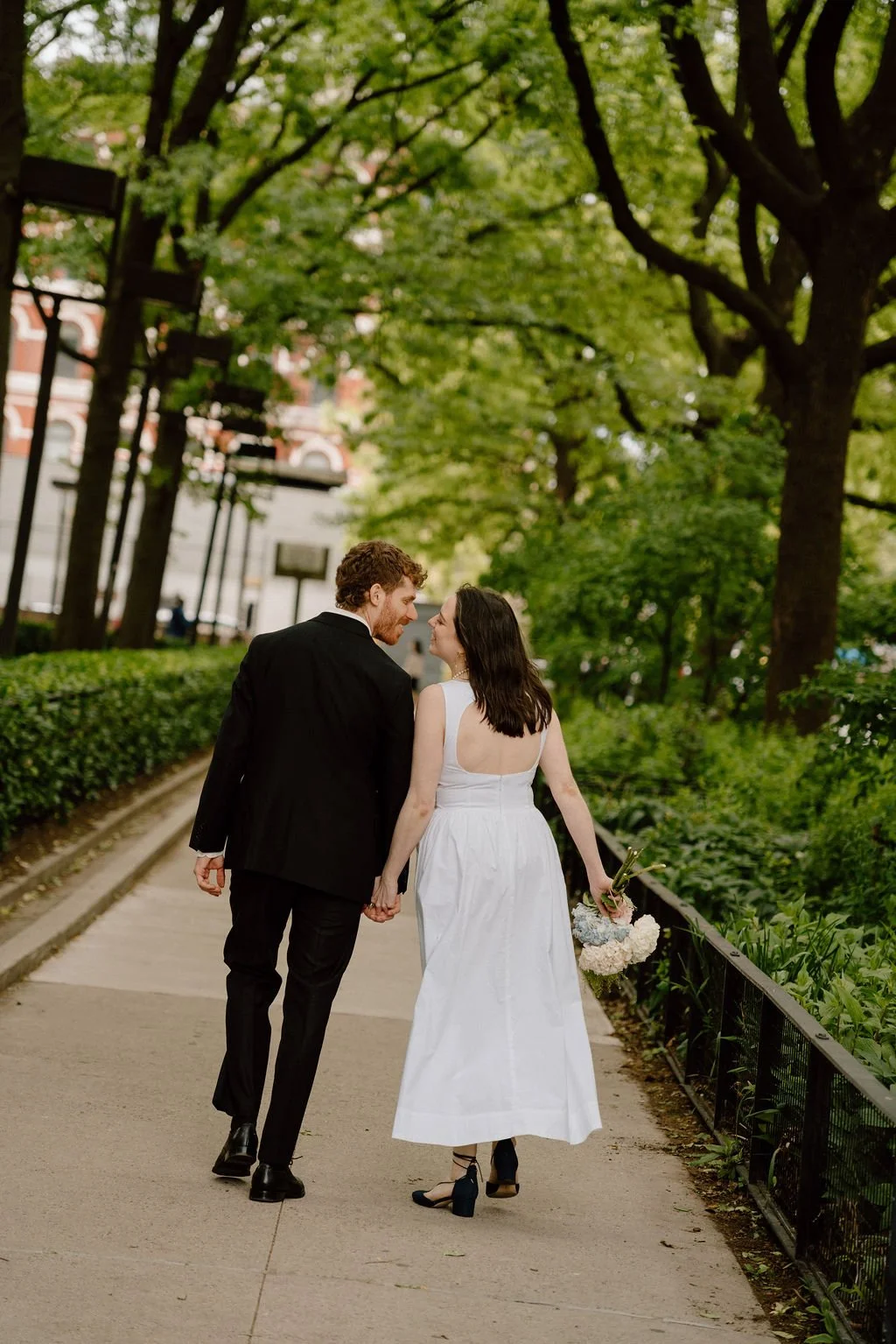 Bride and groom walking through a park after their NYC city hall elopement