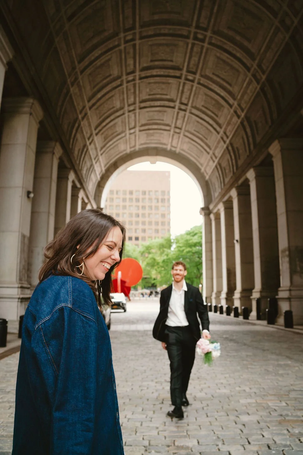 Bride and groom posing beneath the stone archways at New York City Hall following their intimate NYC wedding