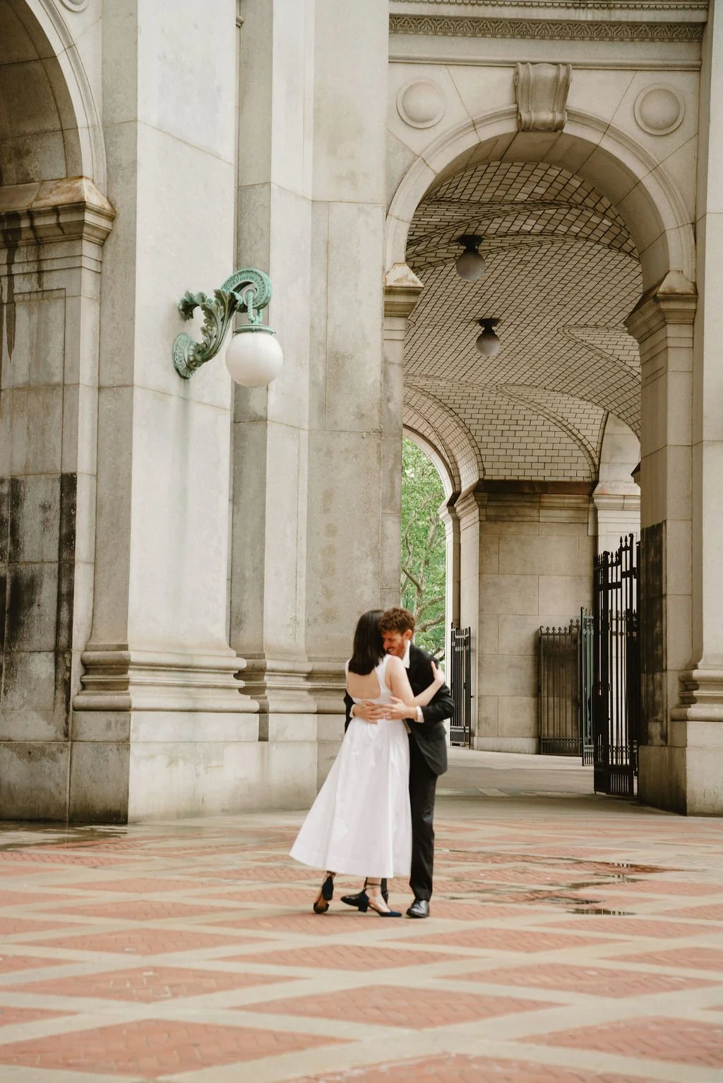 Bride and groom posing beneath the stone archways at New York City Hall following their intimate NYC wedding
