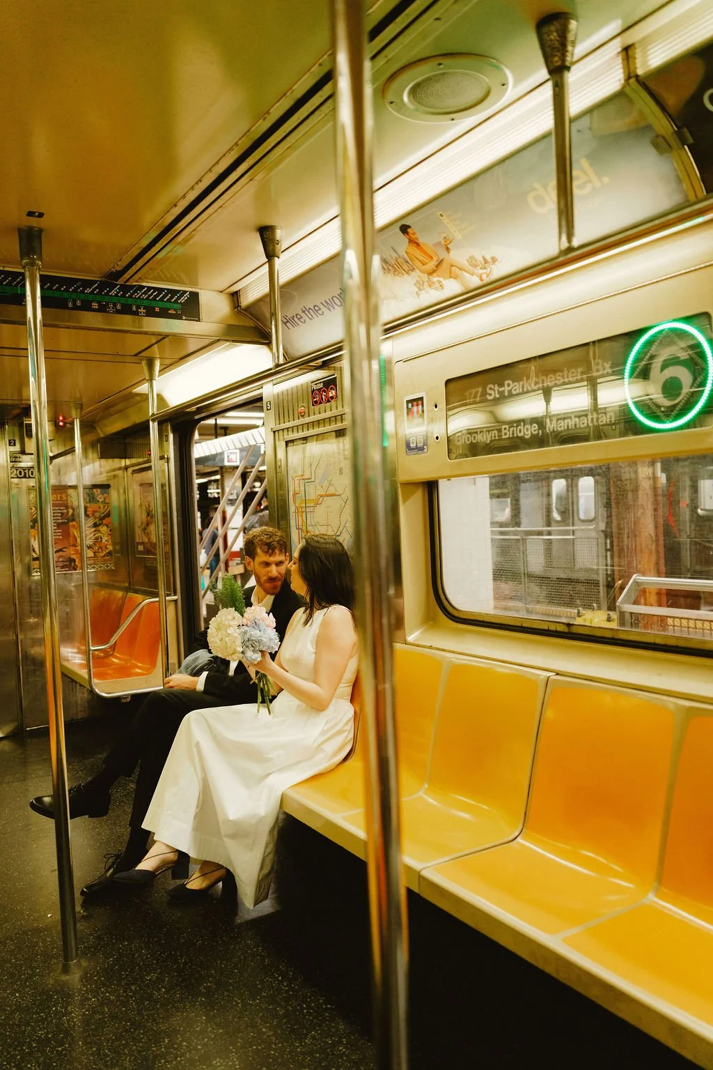 Bride and groom sitting together on a New York City subway train after their NYC City Hall wedding