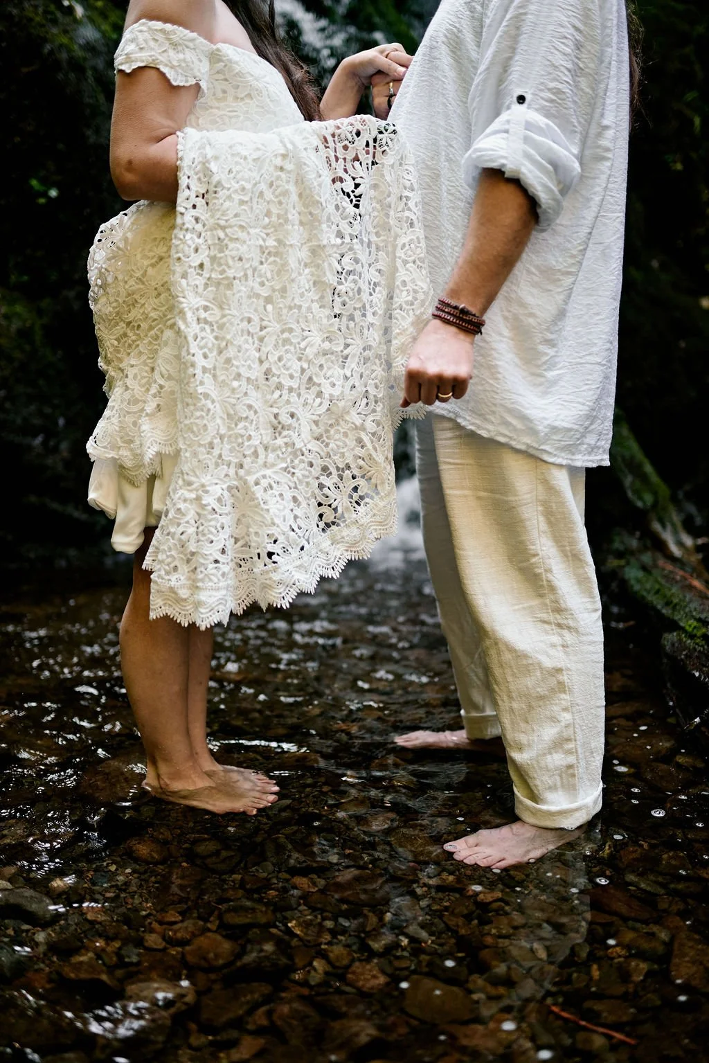 couple exchanging private vows at the base of a small waterfall in quinault rainforest