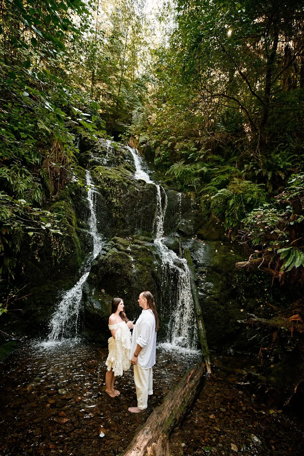 couple exchanging private vows at the base of a small waterfall in quinault rainforest