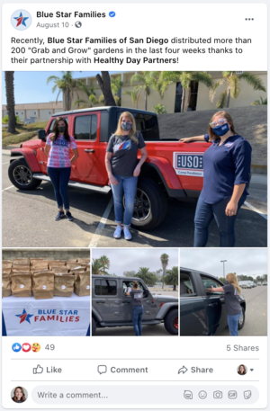 Four women wearing masks standing next to a red pickup truck with a donation sign, in front of a left side view of a silver pickup truck with women loading or unloading boxes, and a small logo for Blue Star Families with a pile of brown boxes.