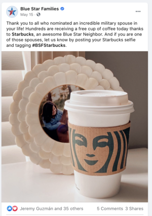 A Starbucks cup of coffee with a custom paper sleeve featuring a smiling face graphic, placed in front of a decorative beige mirror with a scalloped edge.