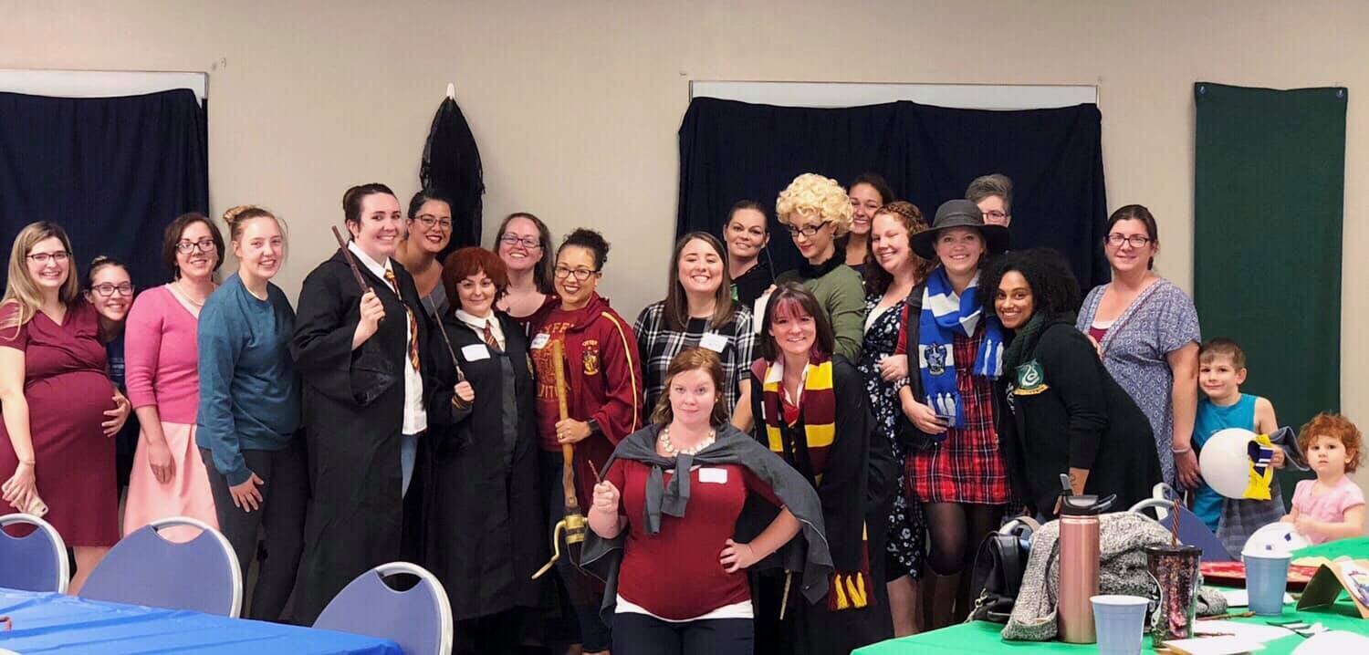 Group of women and children dressed in Harry Potter costumes at a party or event.