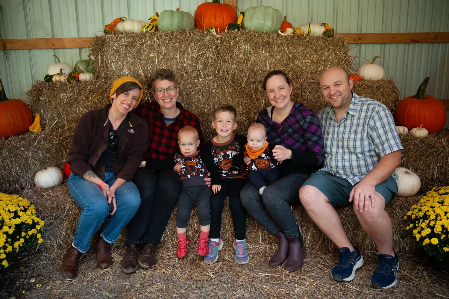 A family photographed in the barn among pumpkins and mums