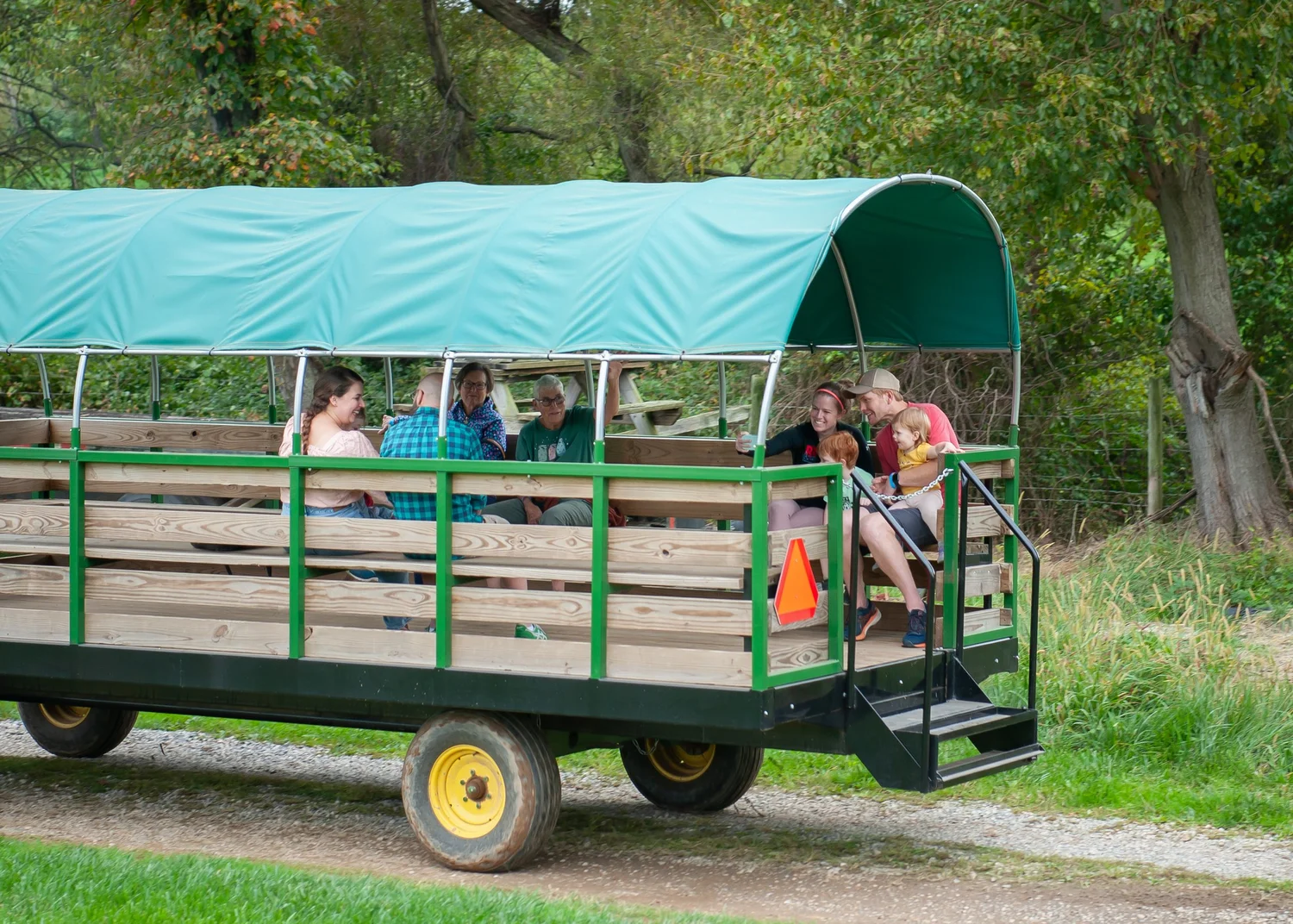 Families riding the covered wagon around the farm
