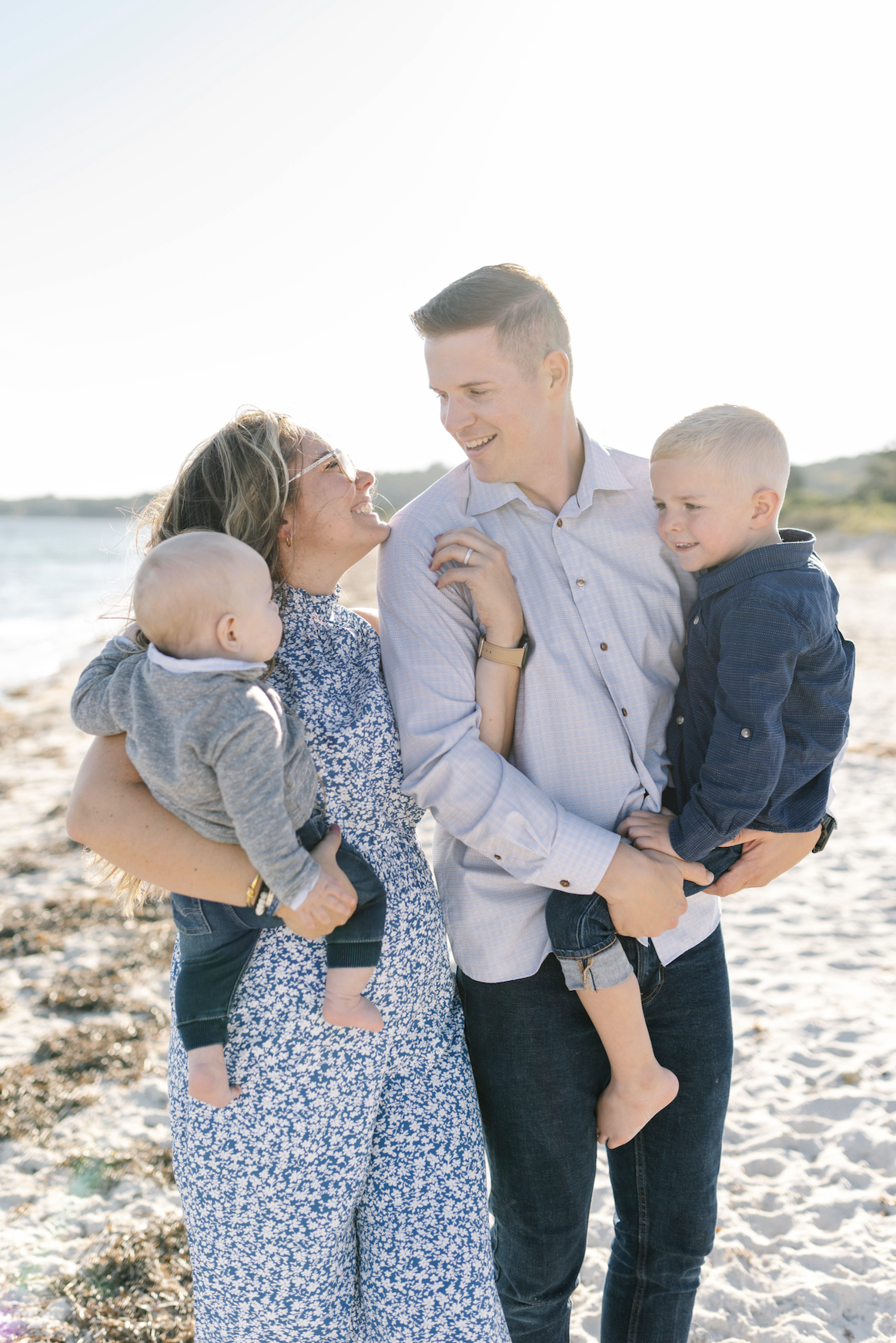 A family of four enjoying a day at the beach, smiling and laughing together.