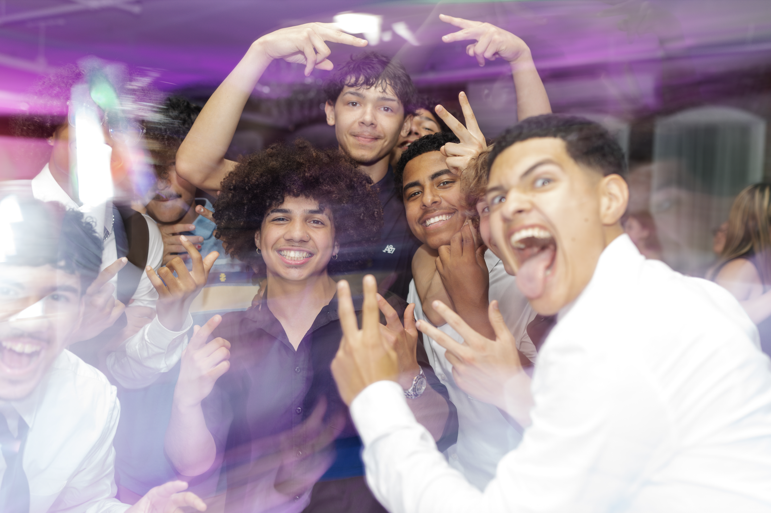 Group of young people smiling and making playful gestures at a party or celebration.
