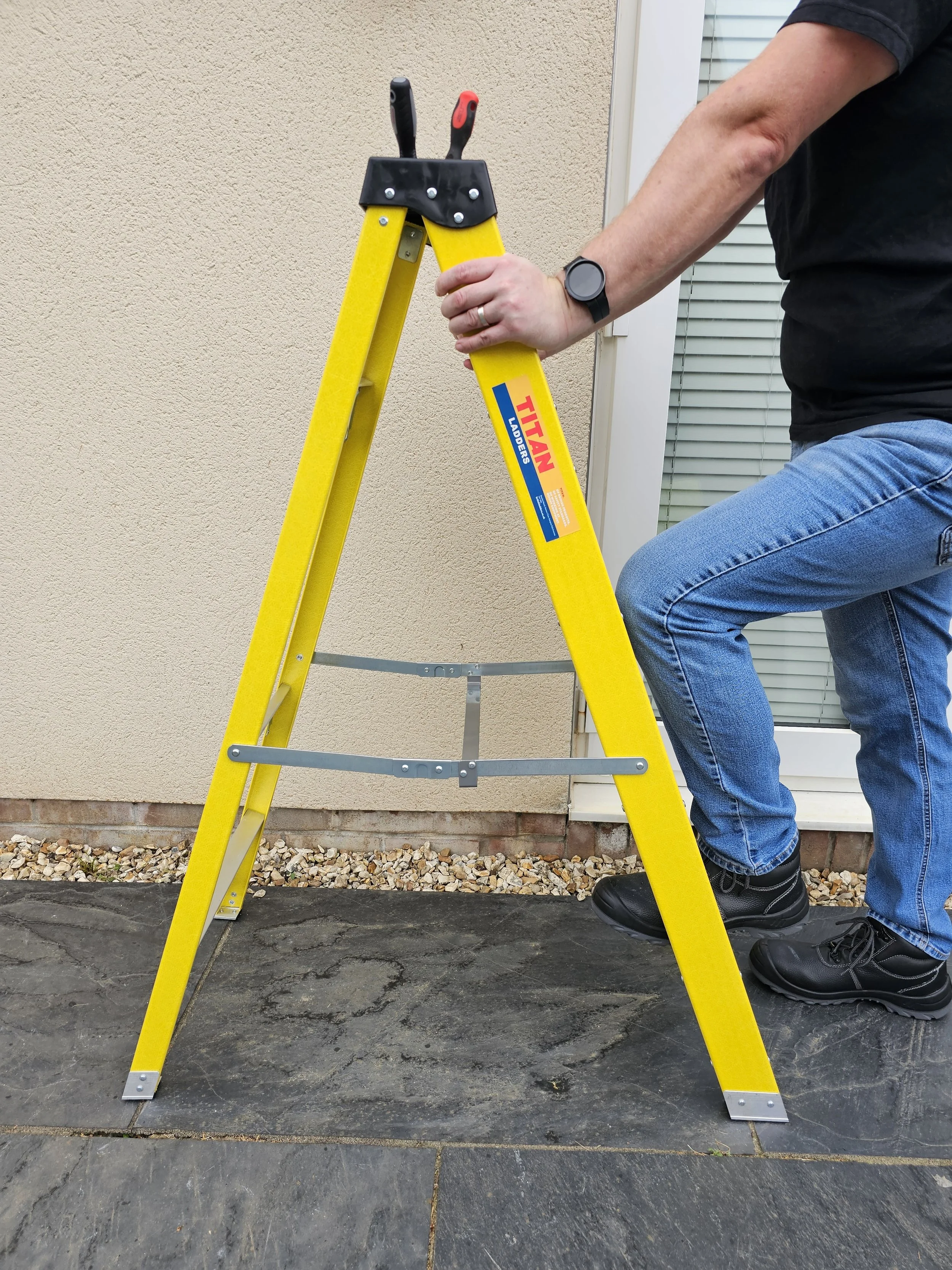 Electrician using a step ladder for outdoor lighting installation