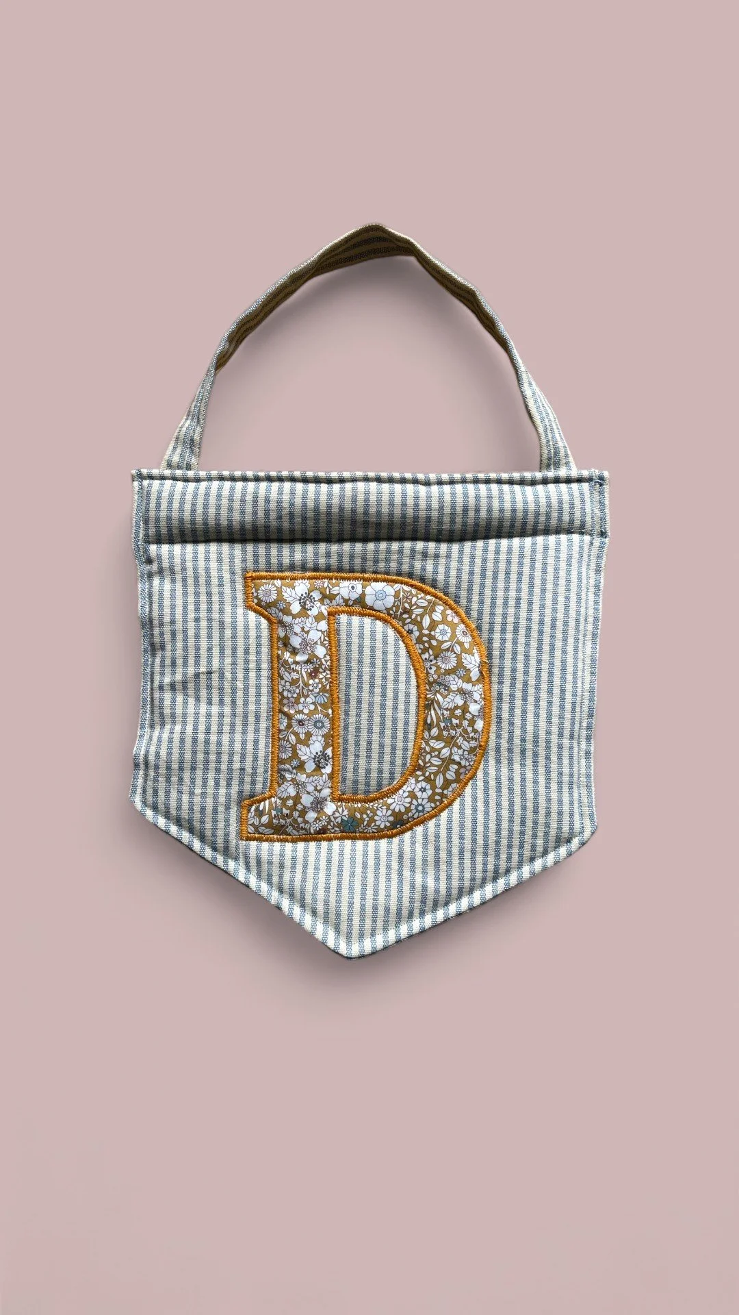 Striped fabric pennant with floral letter D.