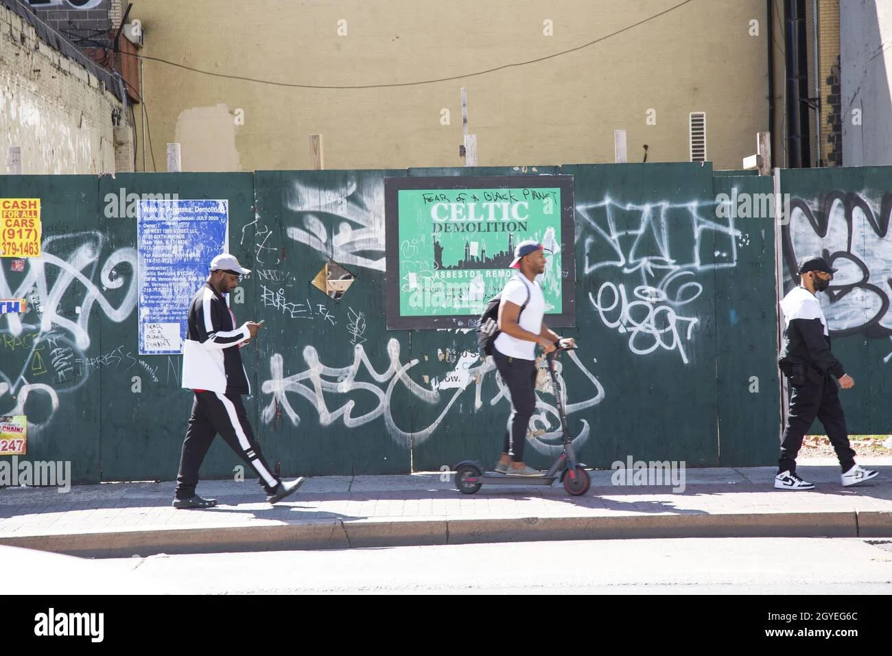 people-walk-past-a-construction-site-on-125th-street-in-the-harlem-nyc-2GYEG6C.jpg