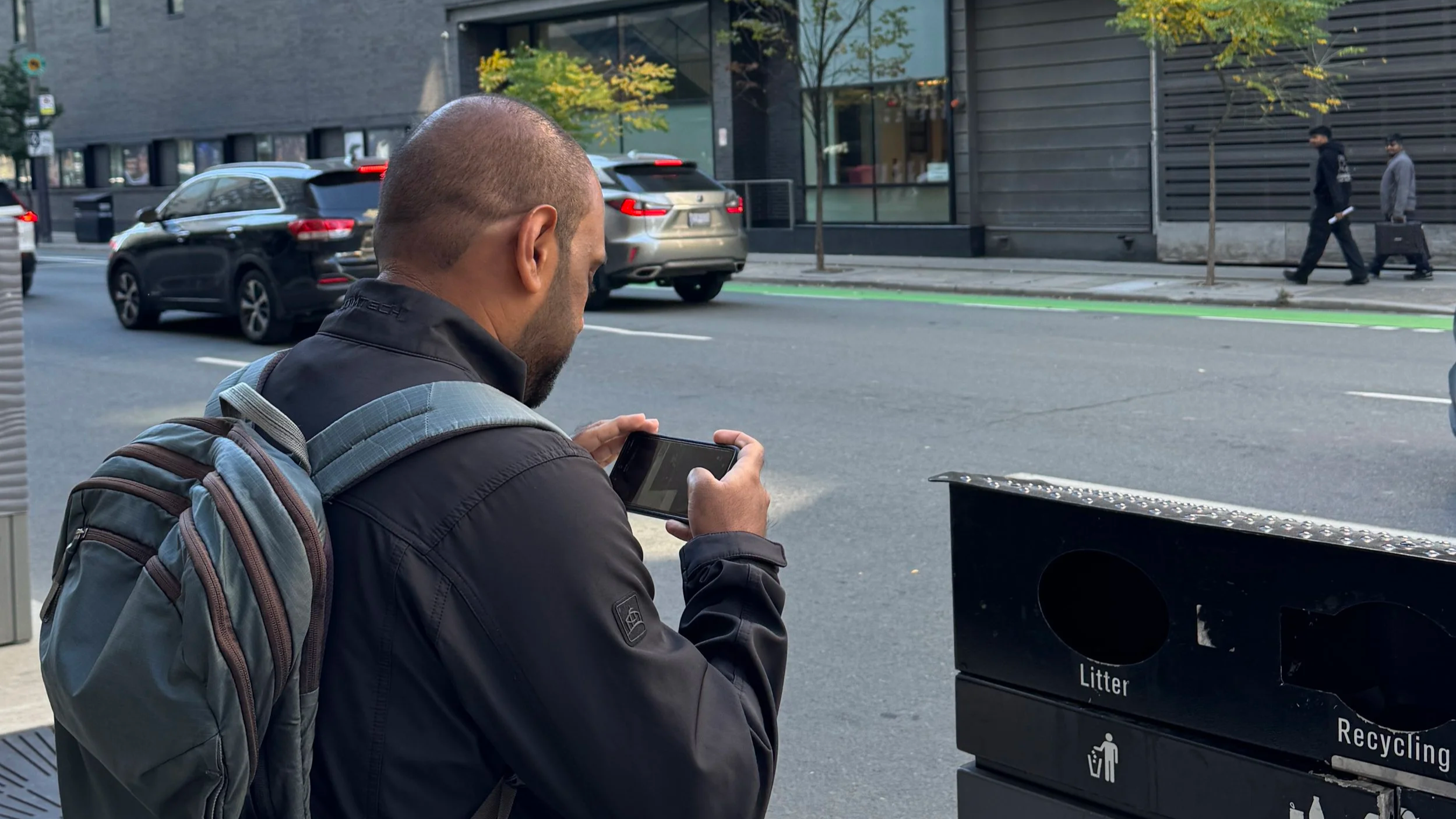 A man takes a picture of a litter bin.