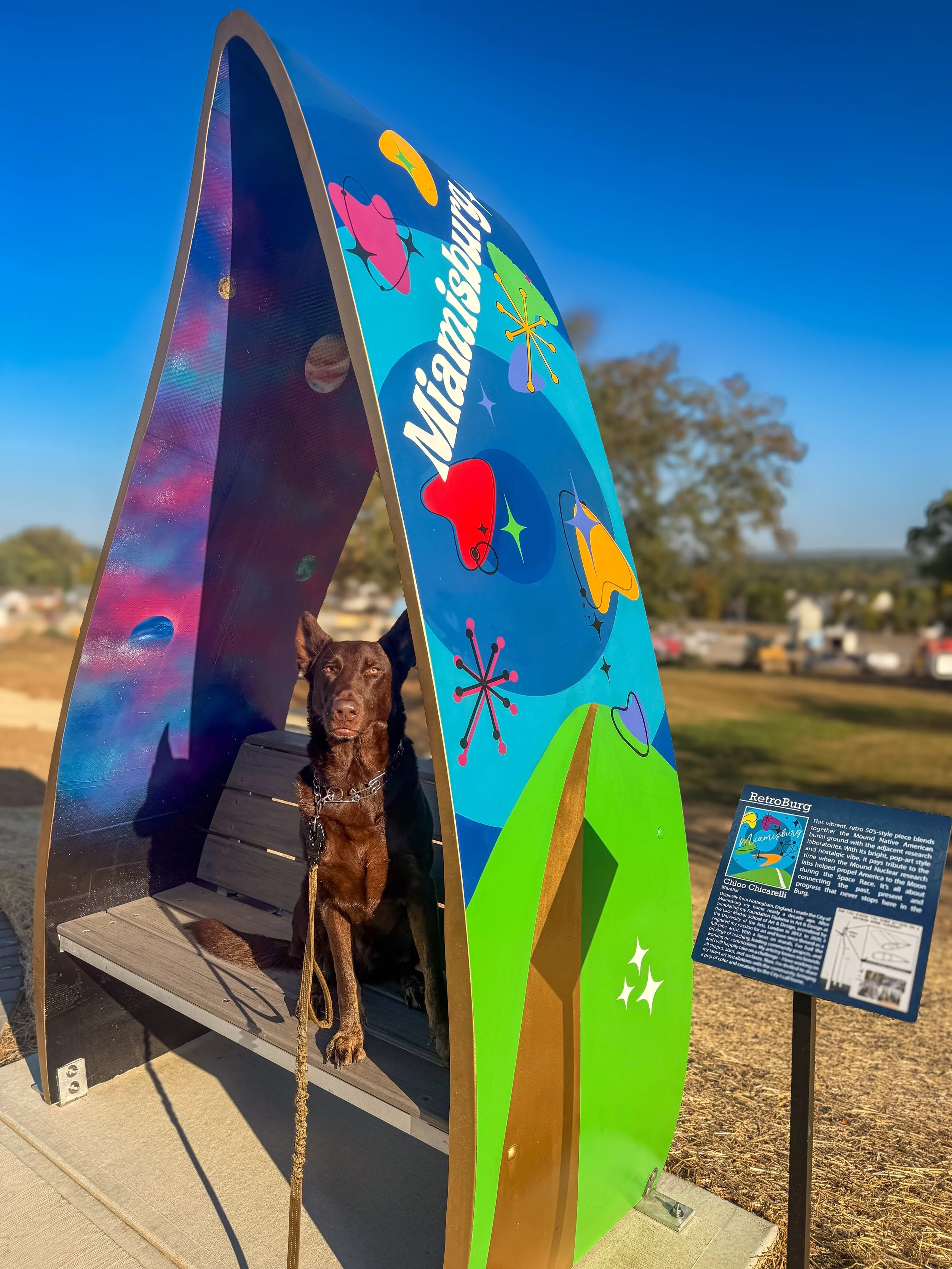 German shepherd sat in painted wind turbine bench art installation