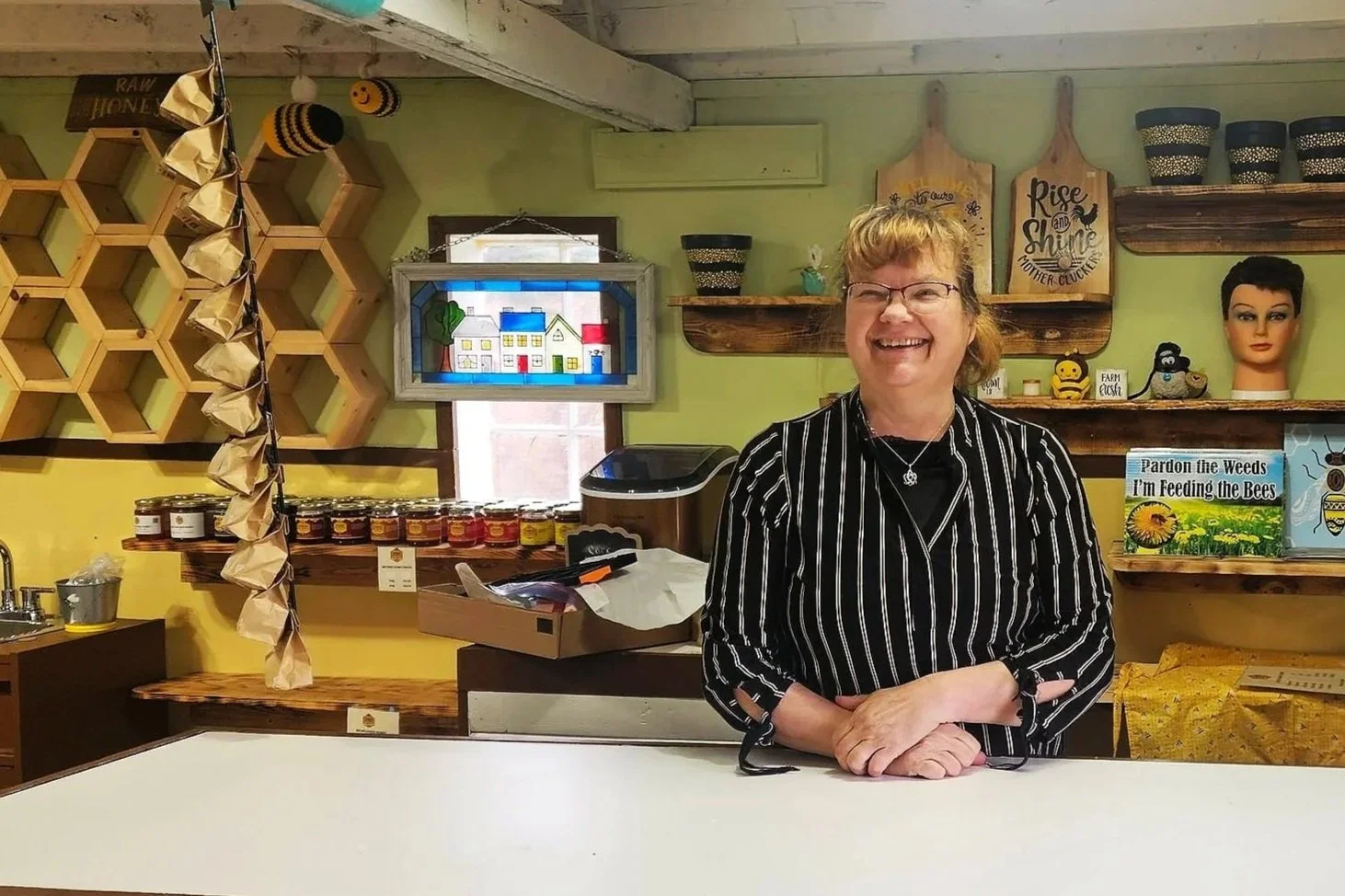 A person standing and smiling behind a desk at a honey company
