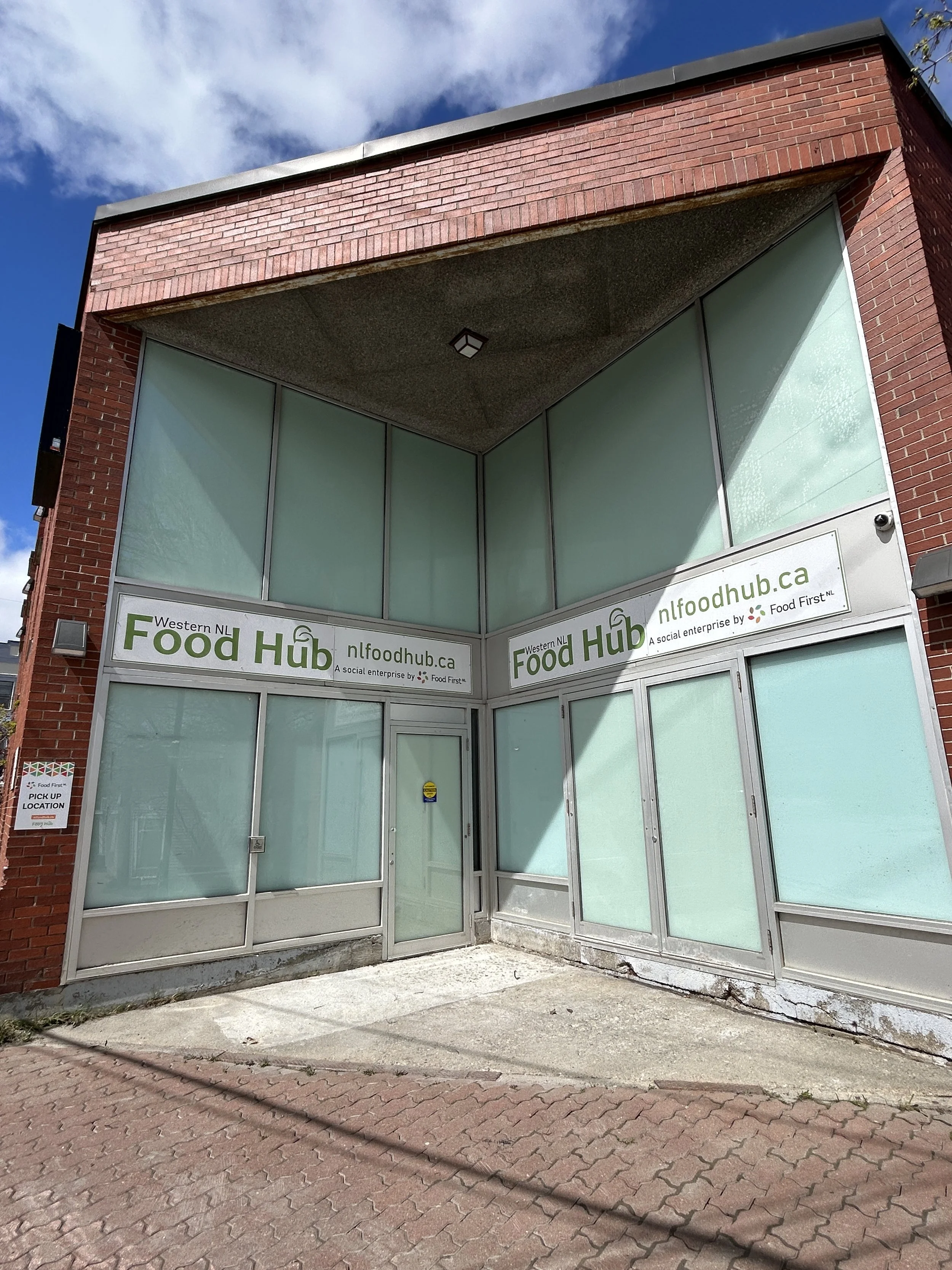 The Western NL Food Hub's building exterior, featuring large windows on a redbrick building and Food Hub signage.