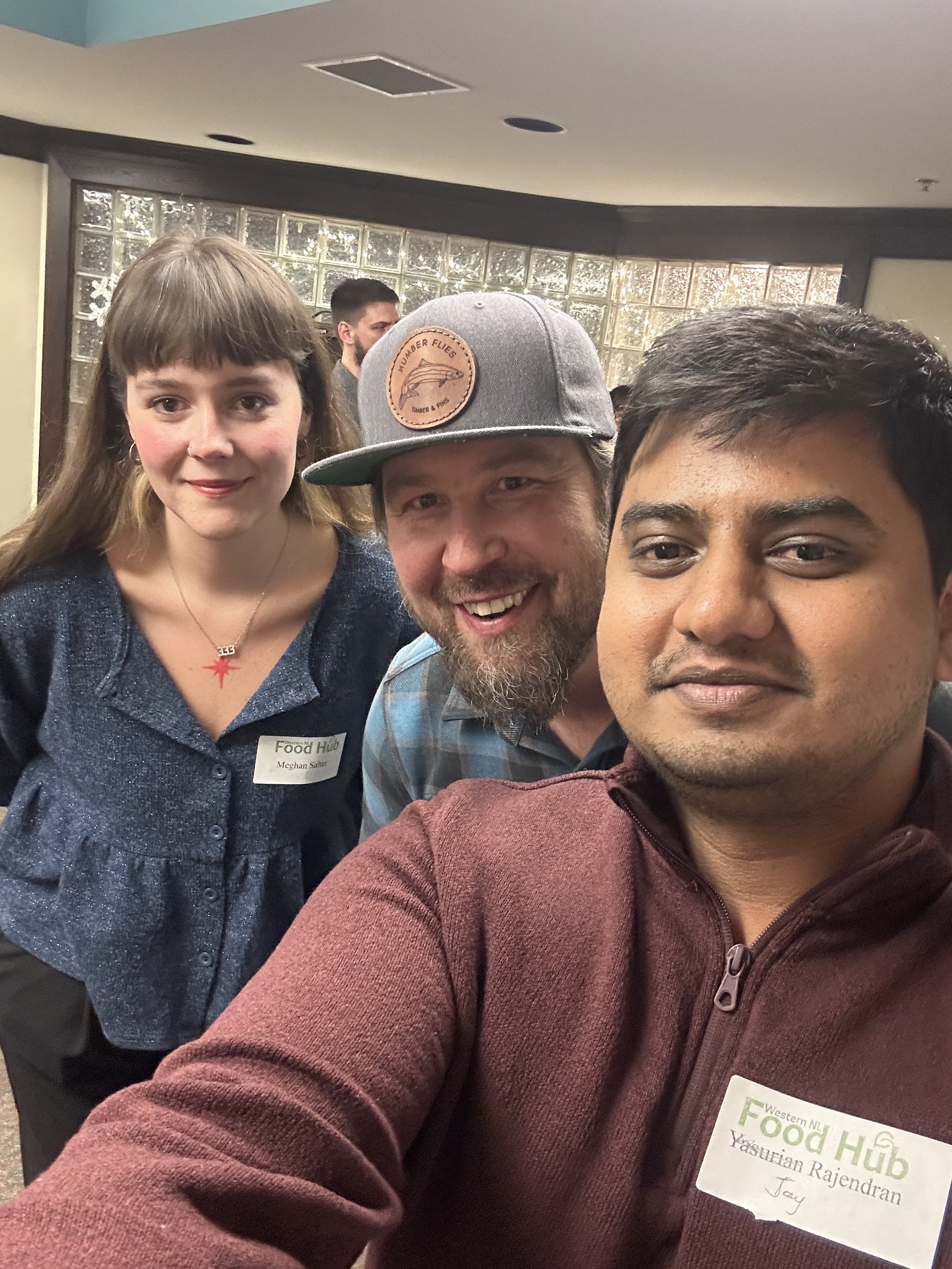 A woman and two men taking a selfie, smiling at the camera.