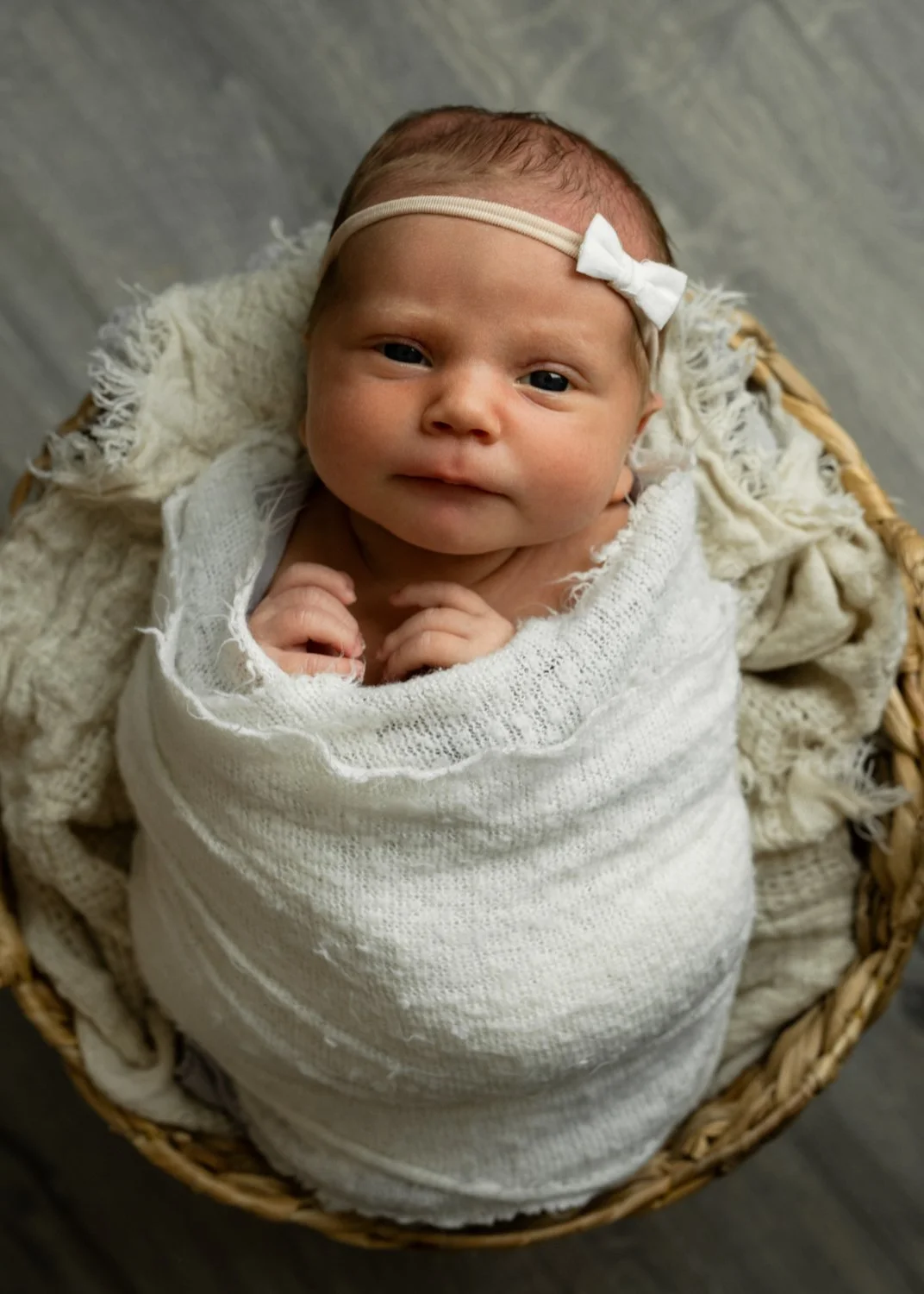Cute awake baby wrapped and posed in basket during this in-home newborn session