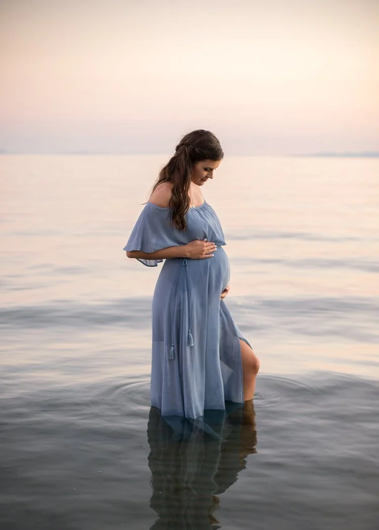 Sunset maternity session at Crescent Beach with mom-to-be wearing blue dress and standing in water
