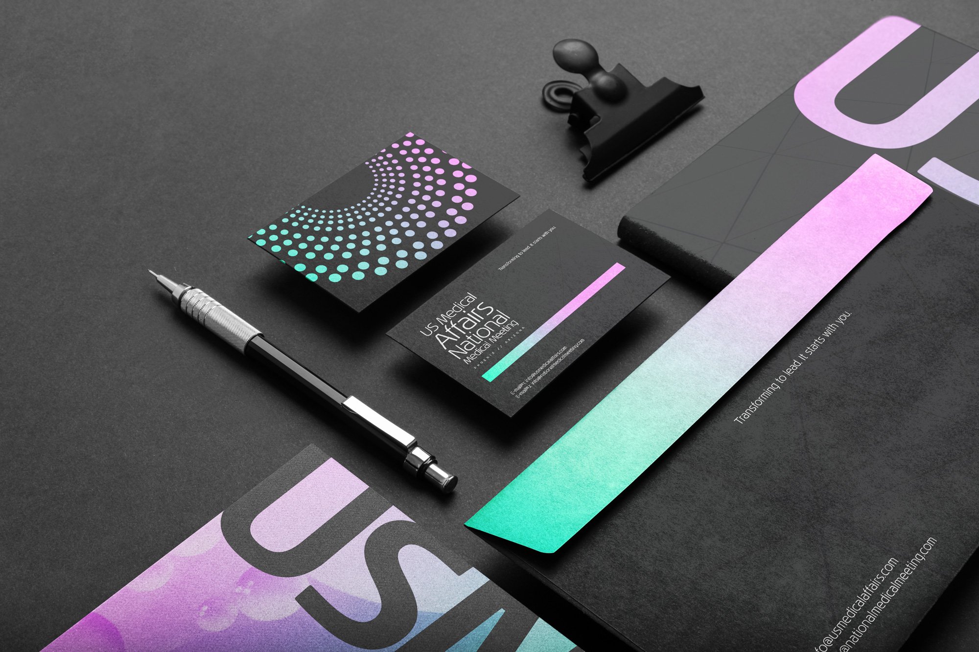 Business branding materials with black, purple, teal, and pastel colors, including a business card, a letter, a pen, a binder clip, and a colorful design element on a black surface.