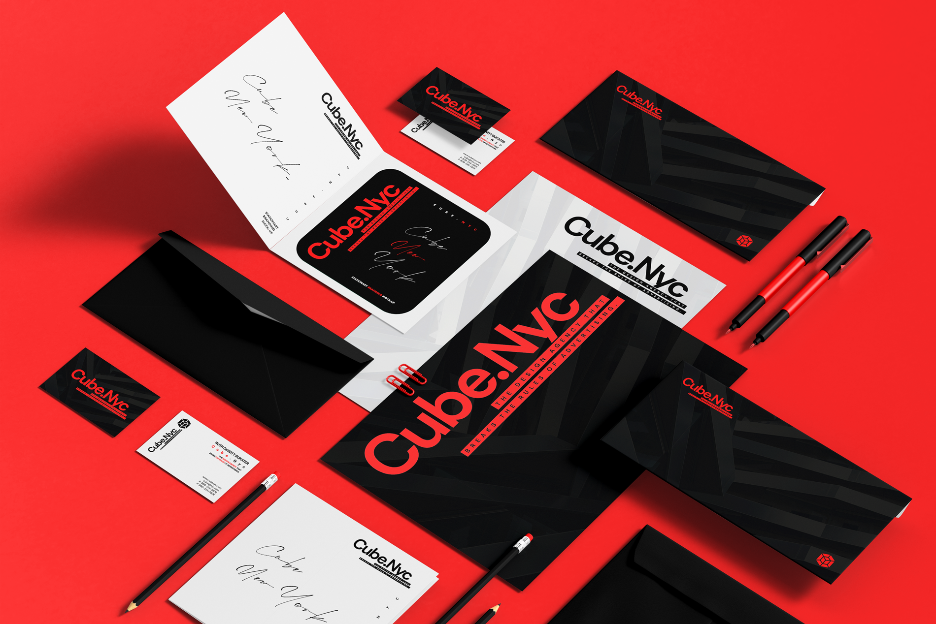 Collection of corporate branding materials including business cards, envelopes, pens, letterheads, folders, and promotional items with a black, white, and red color scheme for Cube.NYC, an advertising agency.