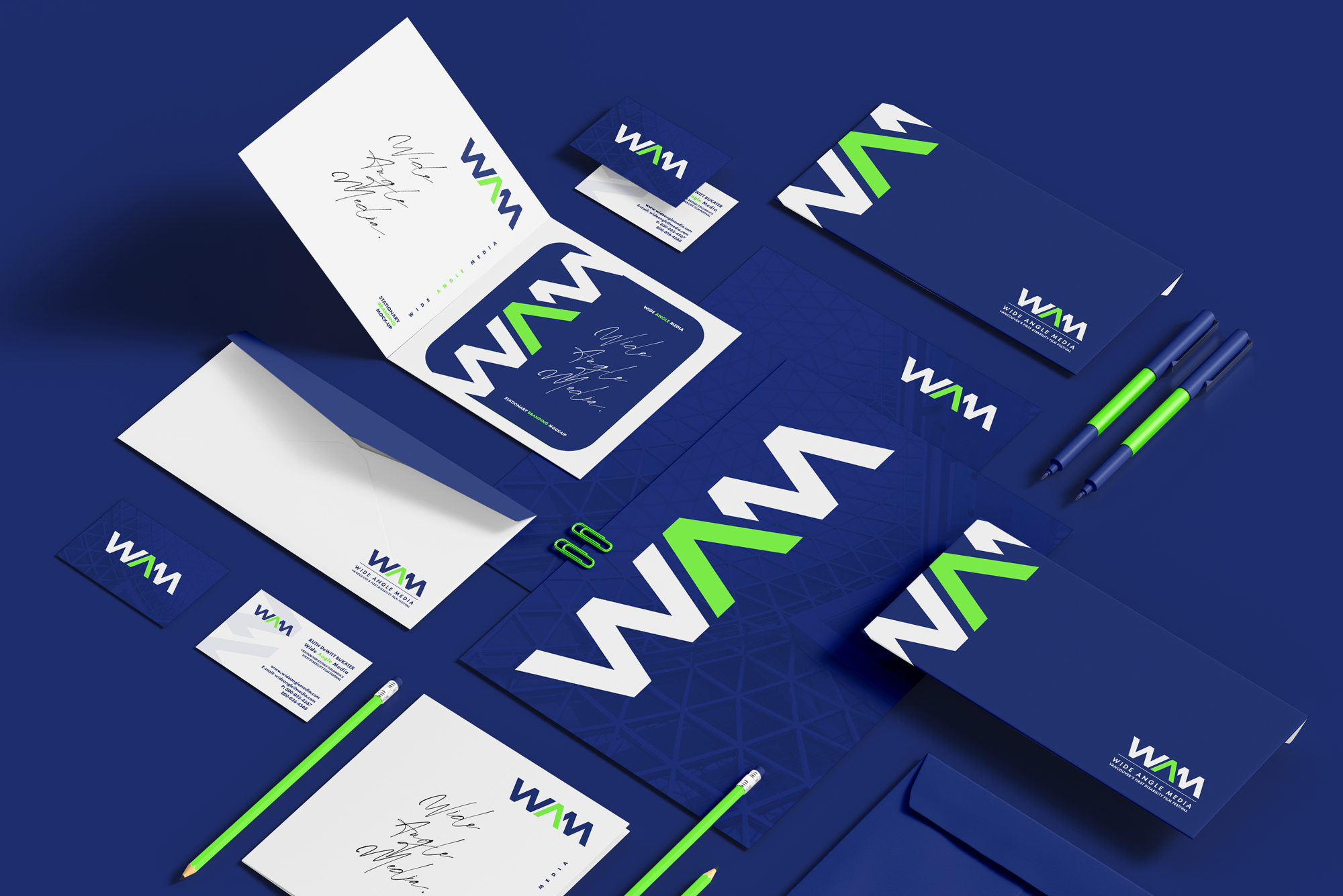 A collection of branding stationery items including business cards, envelopes, folders, pens, and presentation folder, all featuring a corporate logo with the initials WAM in white and green on a blue background.