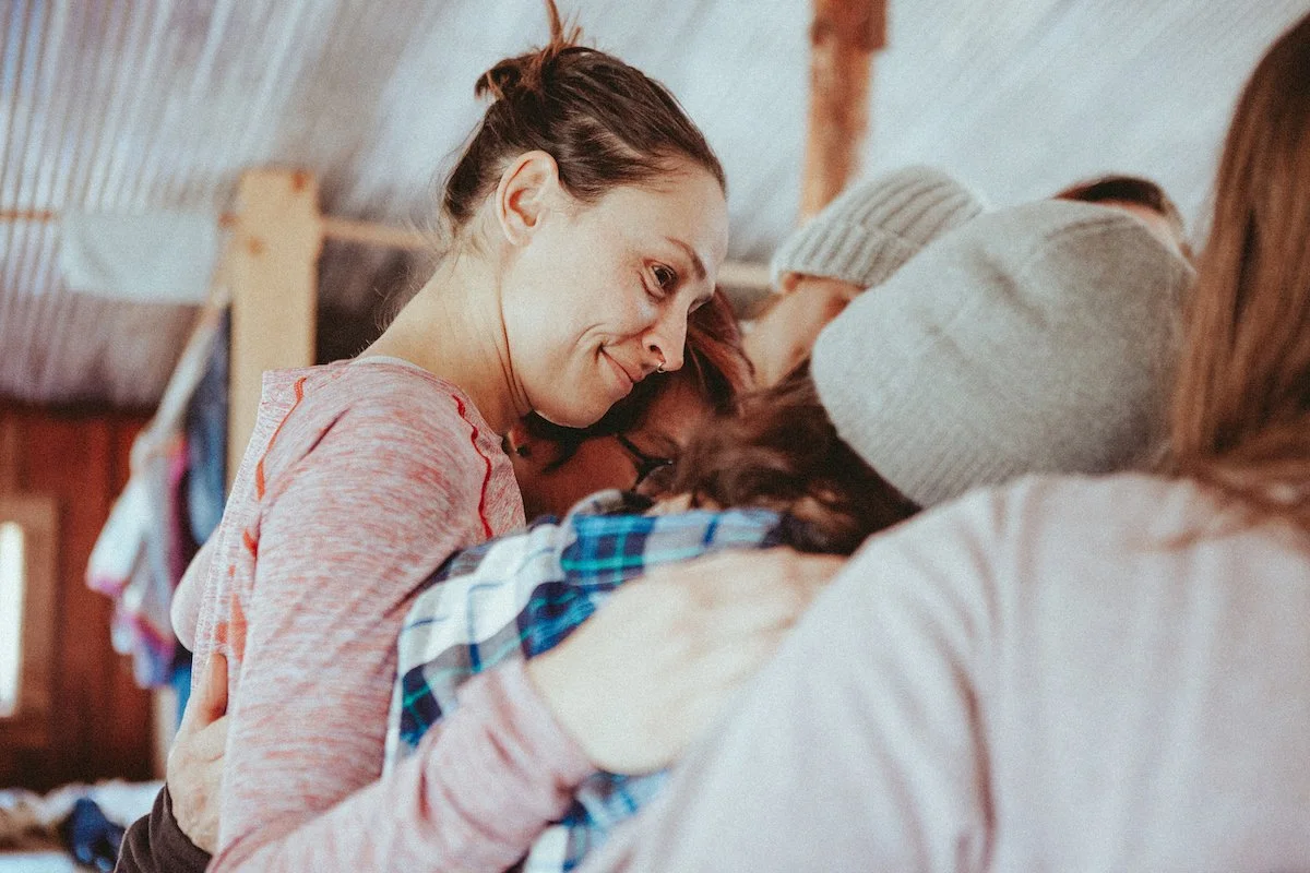 A group of people hug each other closely, showing affection and comfort.