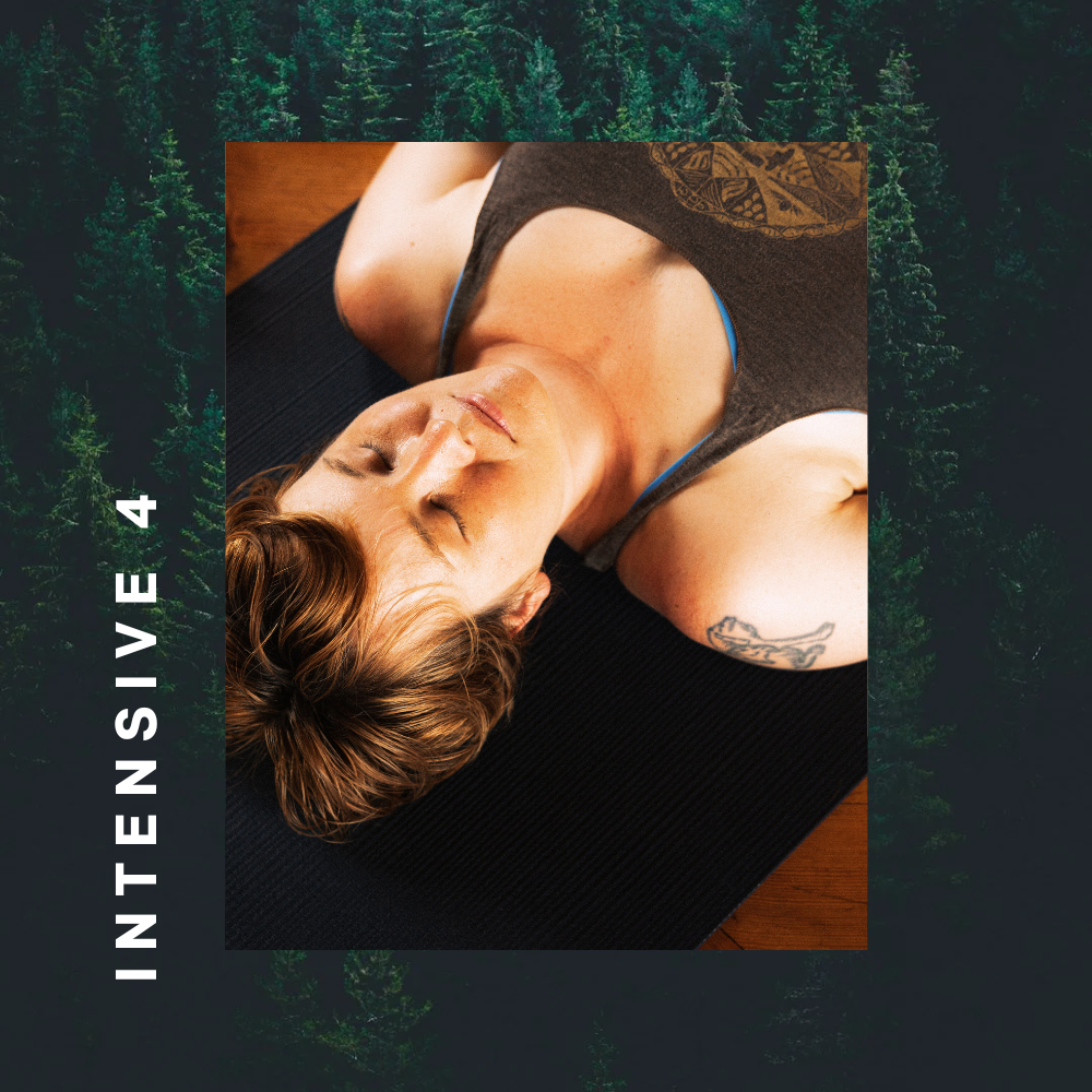 A woman with short brown hair lying on her back on a black yoga mat, eyes closed, in a peaceful indoor setting.