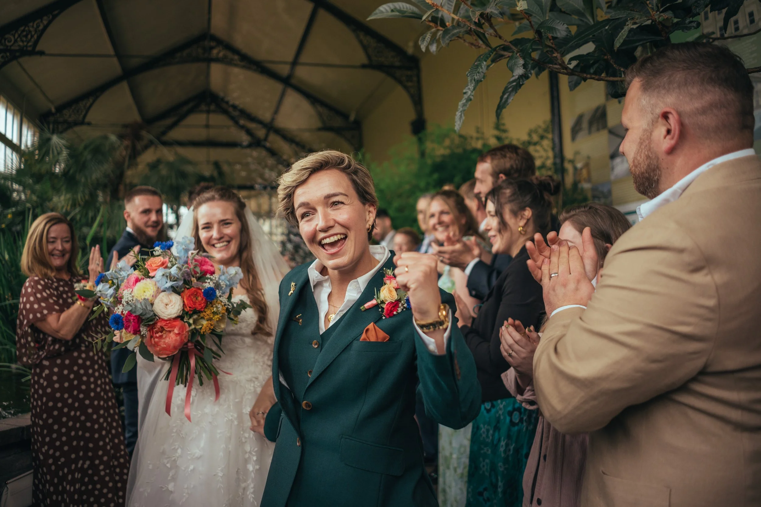 2 Brides leaving their ceremony, bride in suit, bride in a dress
