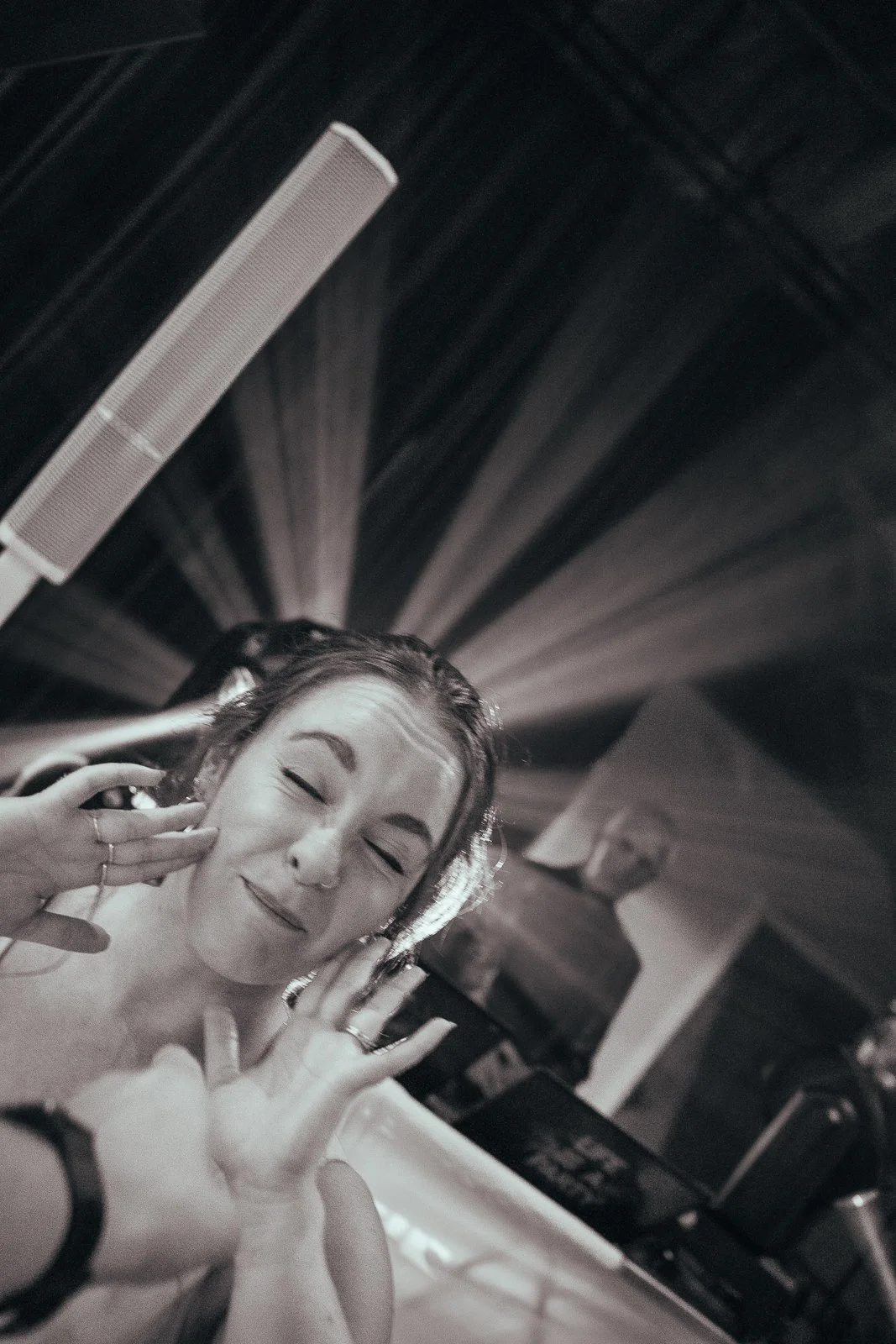A woman dancing and singing, touching her face on the dance floor with disco lights behind her.