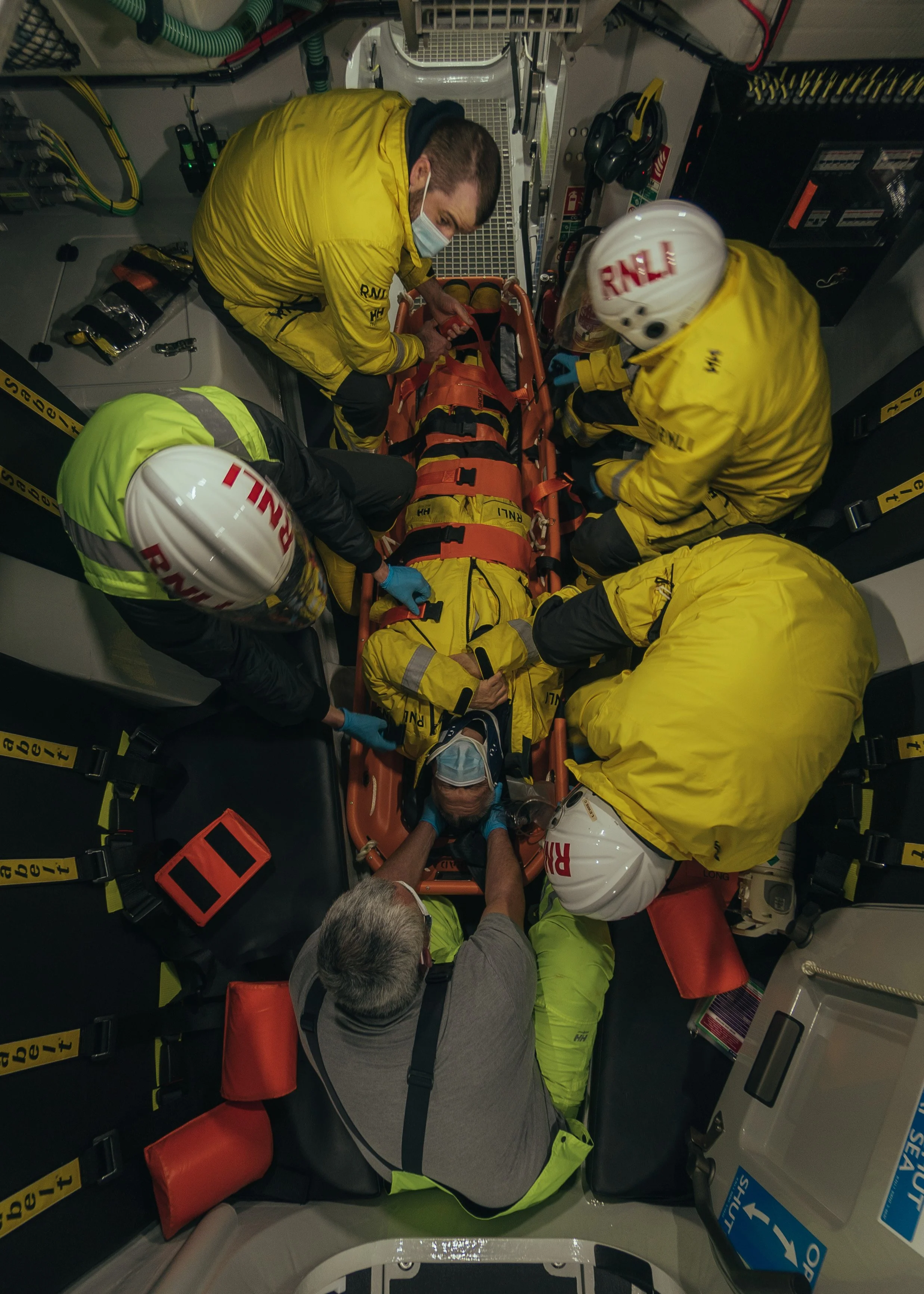 Emergency medical team attending to a patient on a stretcher inside an ambulance.