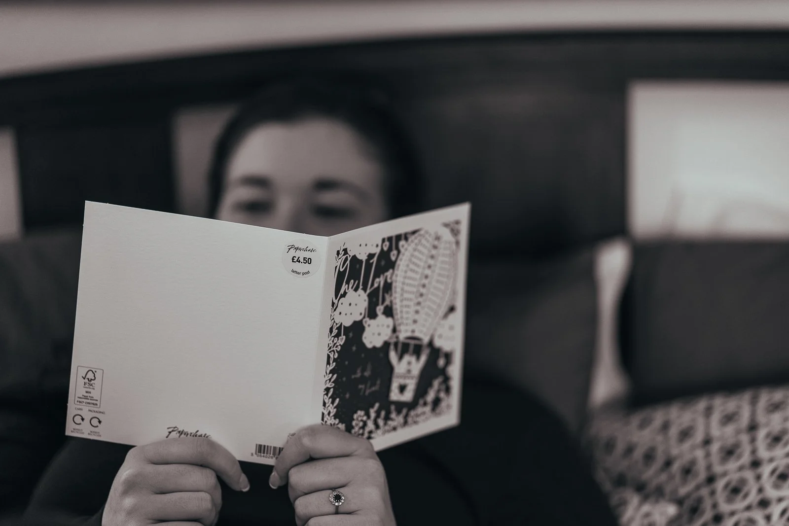 A bride reading a wedding card while sitting on a bed, the price is still on the card £4.50.