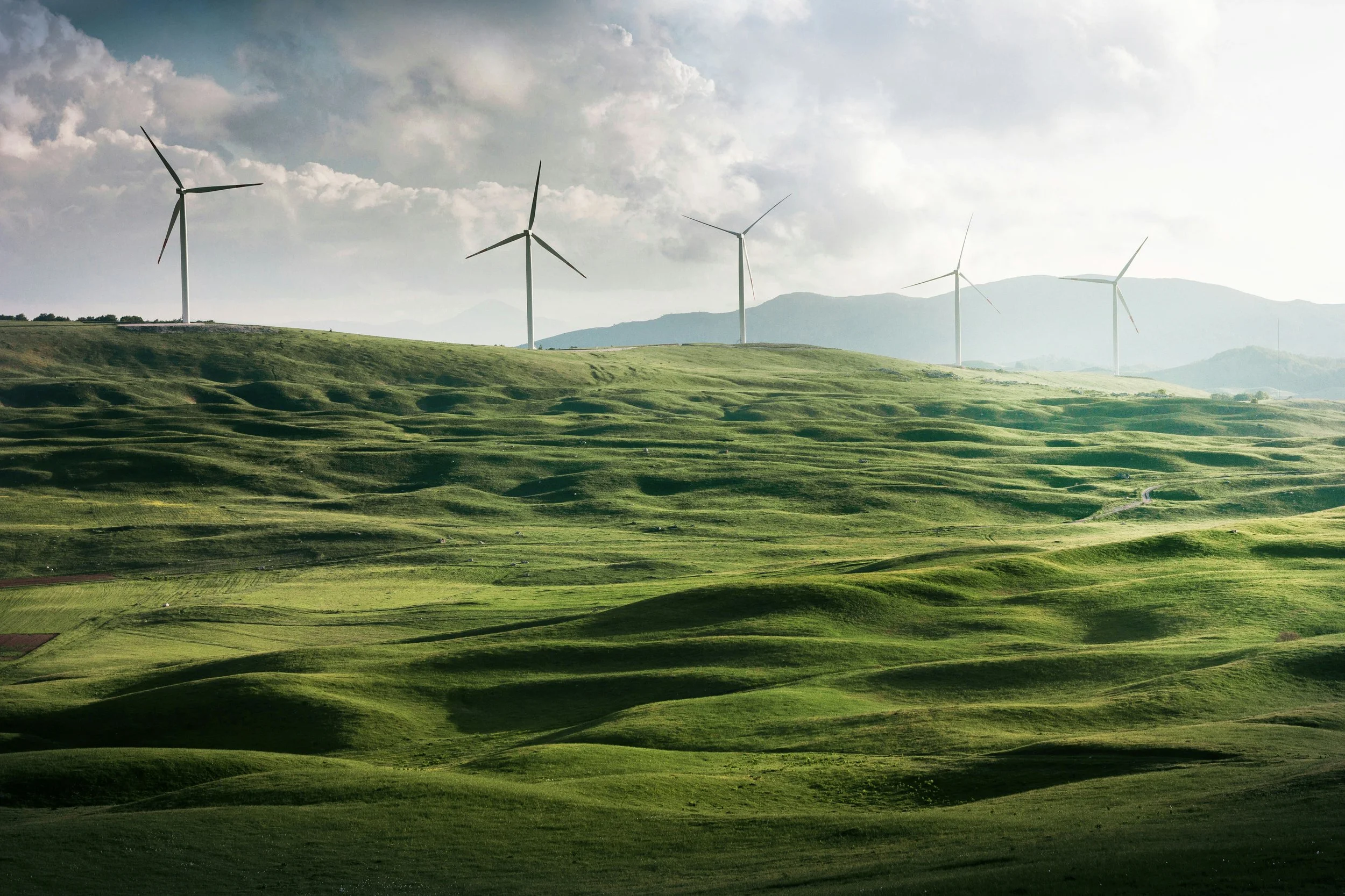 Rolling green hills with wind turbines on a cloudy day.