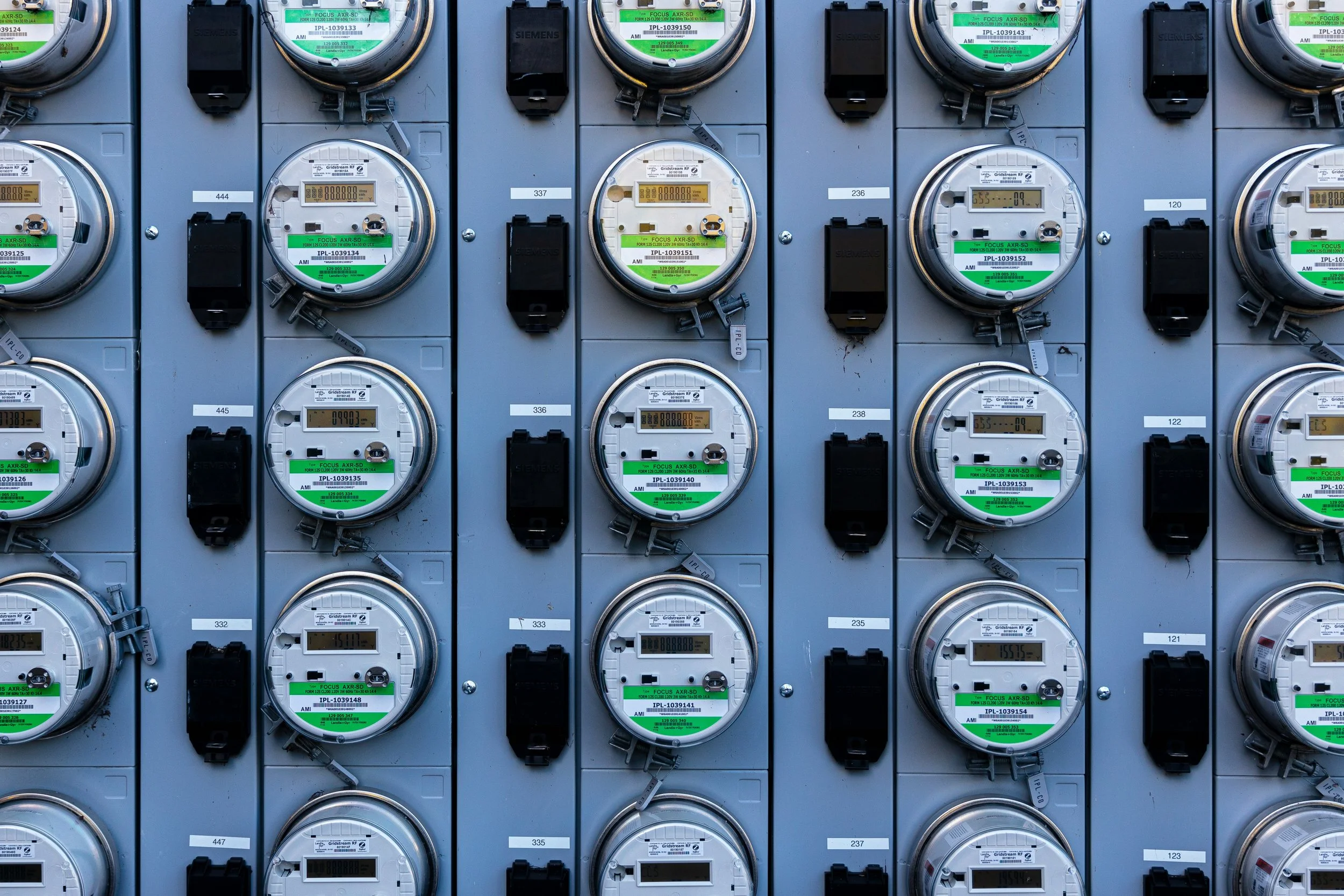 Multiple electric meters mounted on a wall in a grid pattern.