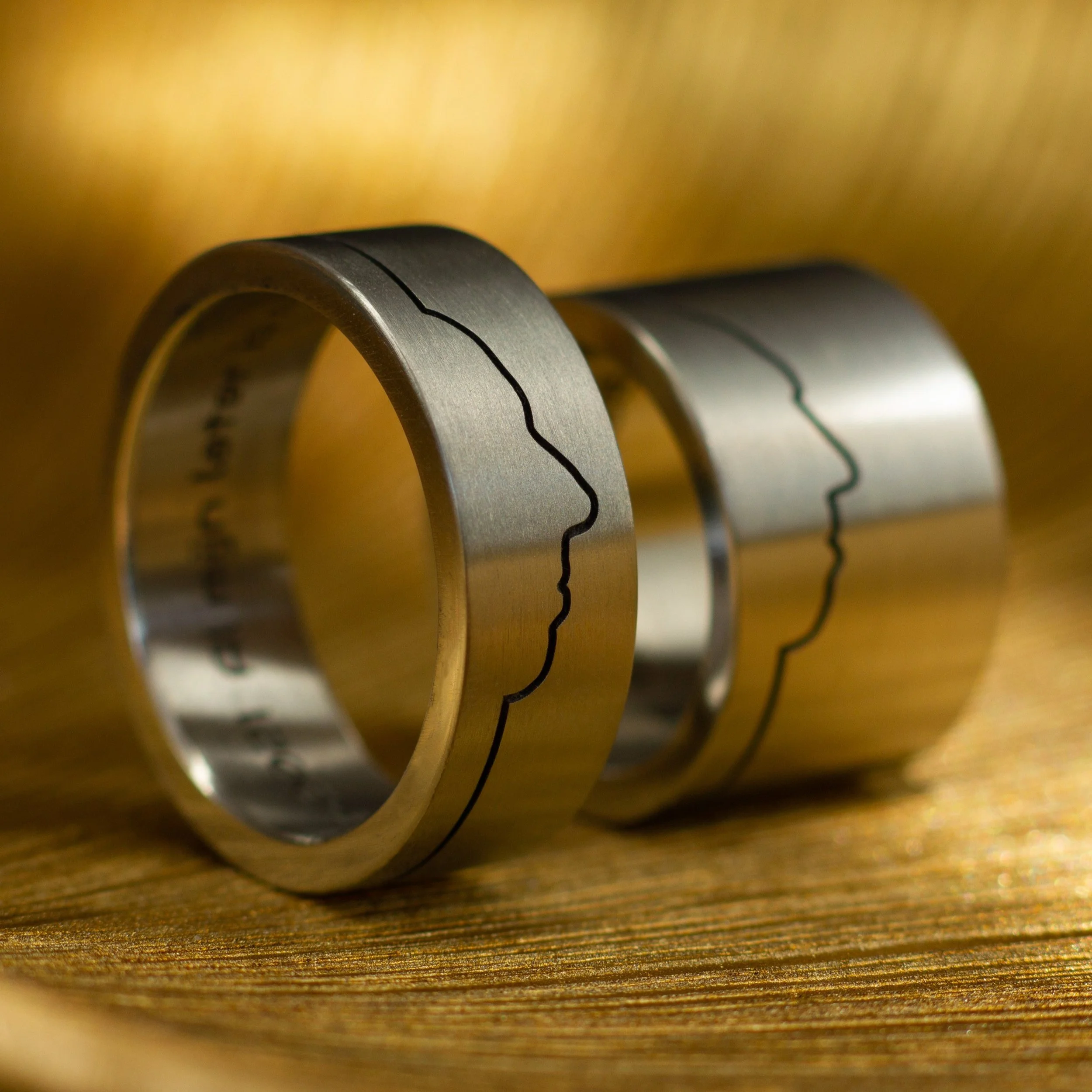 Twee titanium ringen.
Twee gezichtsprofielen.
Twee mensen vereeuwigd in metaal.

Voor deze set hebben we gewerkt met echte profielfoto&rsquo;s van hun gezicht. Op basis daarvan hebben we het silhouet verwerkt in de ring, waardoor er een subtiele lijn