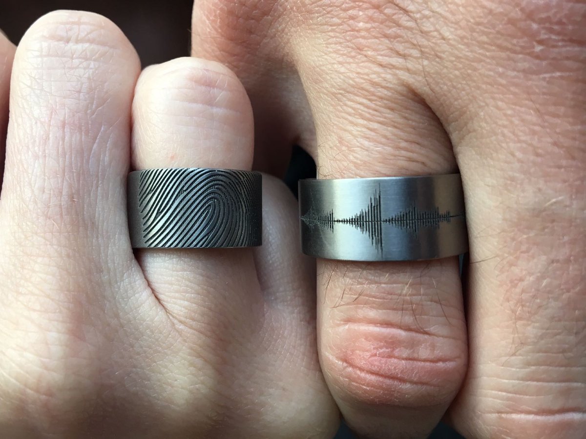 Trouw foto van Twee handringen, één met een vingerafdruk en de andere met een geluidsgolffiguur, gedragen door twee personen. Kool design jewelry