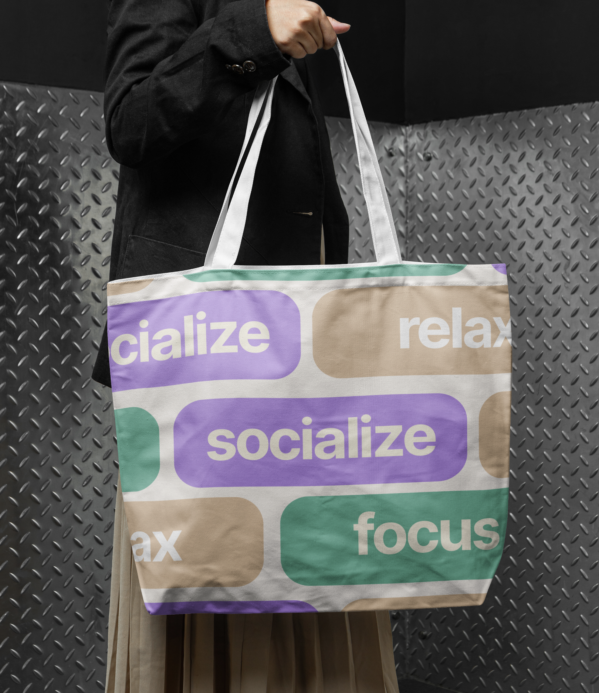 Person holding a large tote bag with words 'socialize', 'relax', and 'focus' in colorful speech bubble designs.