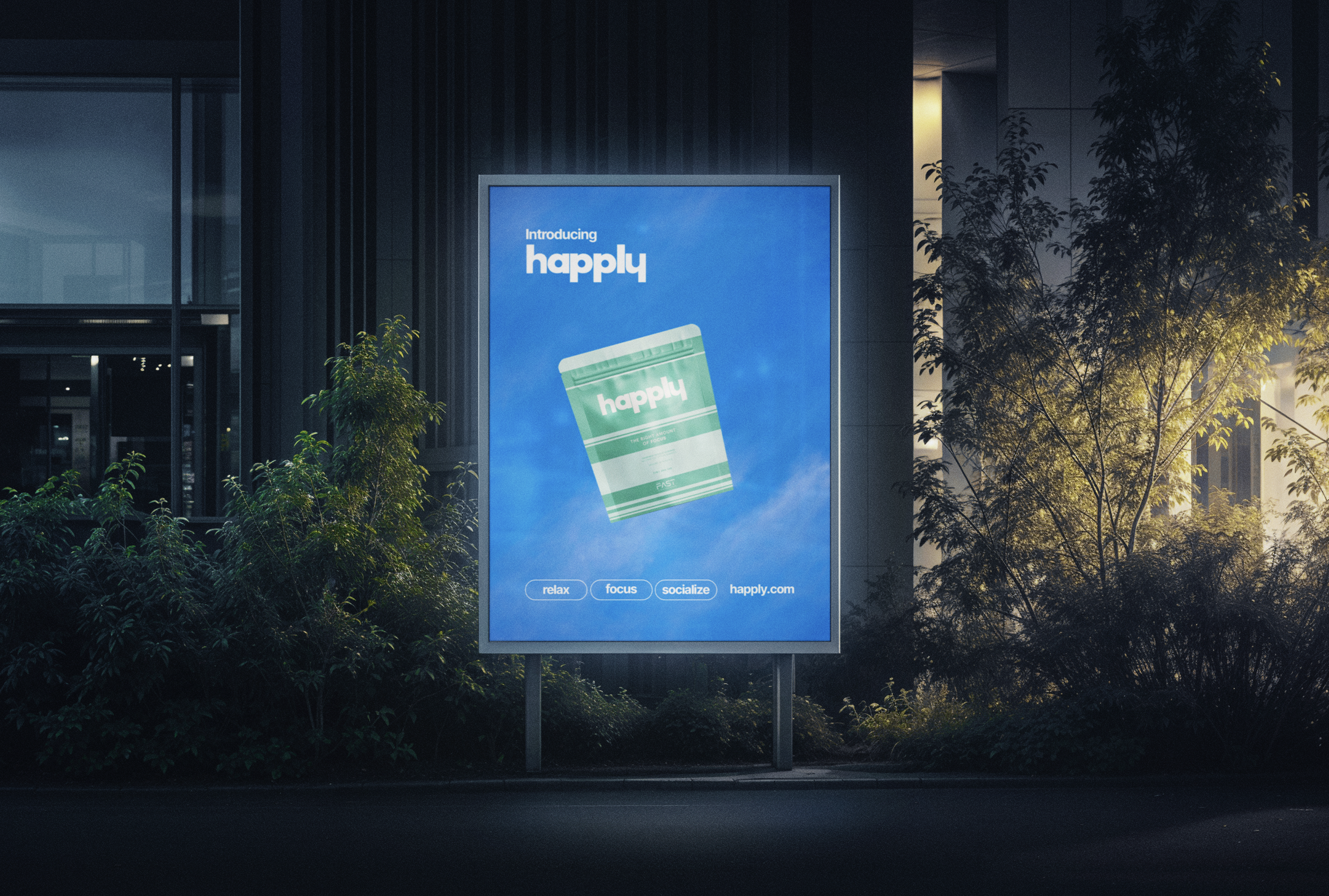 Digital billboard advertisement for a product called 'Happly', featuring a packet with the word 'Happly' on it, with slogans 'relax,' 'focus,' and 'socialize' at the bottom, in an urban setting at night with greenery around.