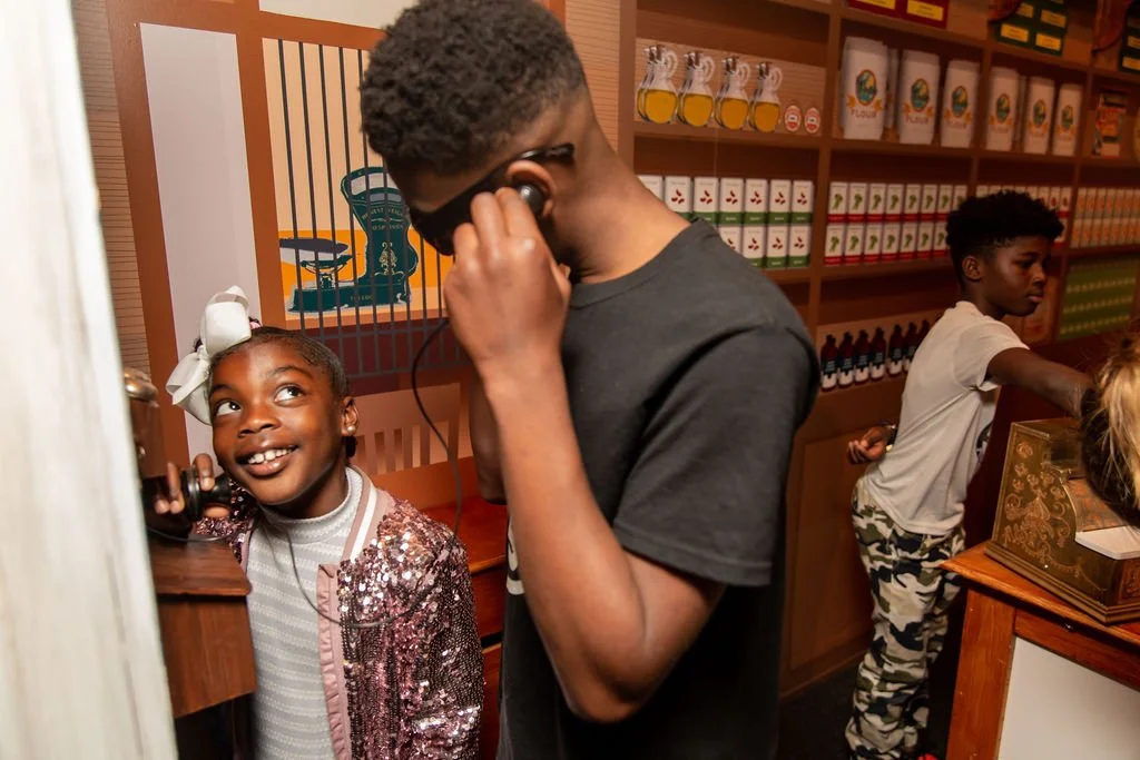 Children playing telephone in the general store exhibit