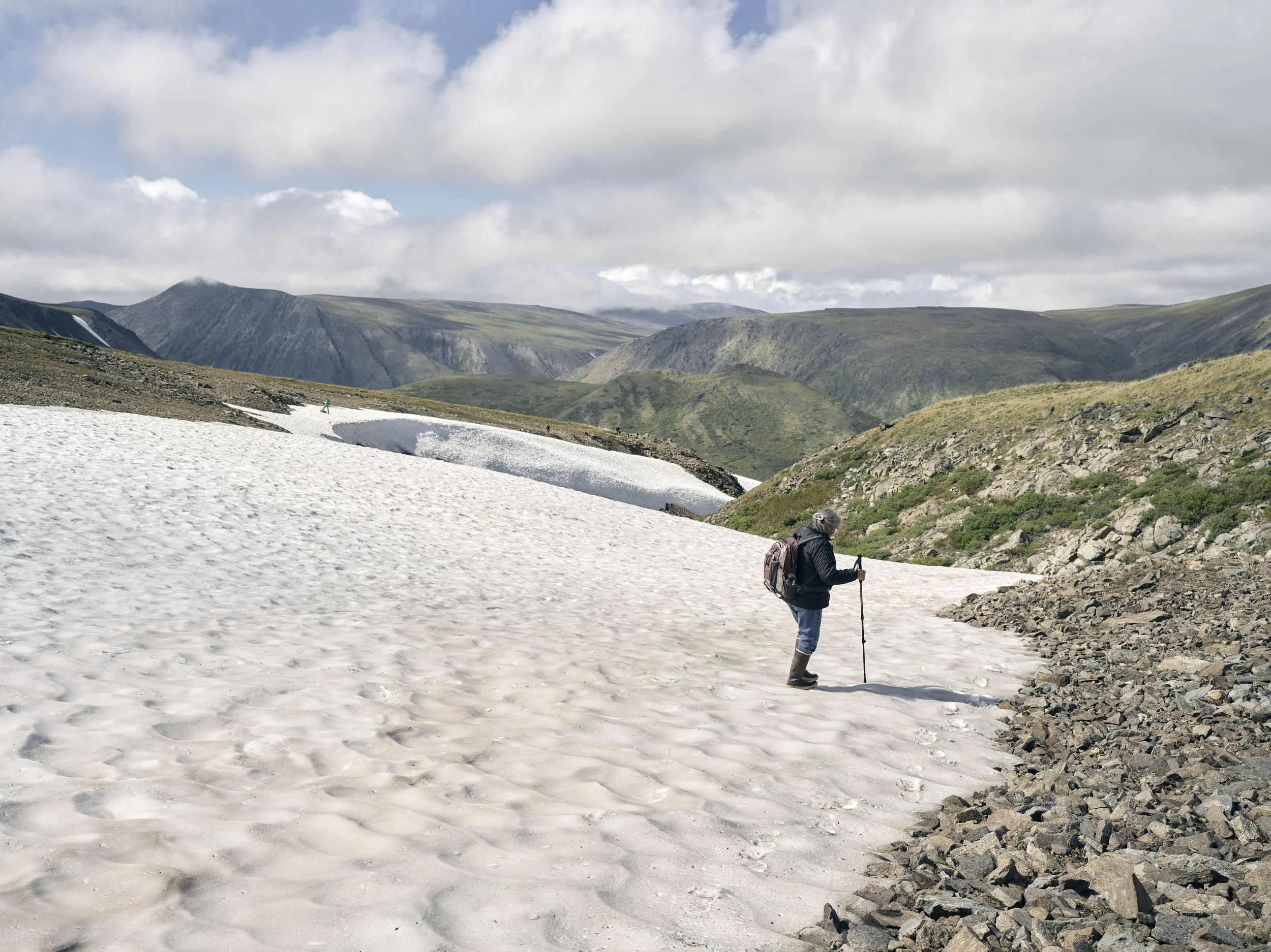 In late summer, researchers move carefully across thinning alpine snowfields on ancestral hunting grounds to document artifacts emerging from retreating ice, under the direction and guidance of the Nations whose territories hold these histories.