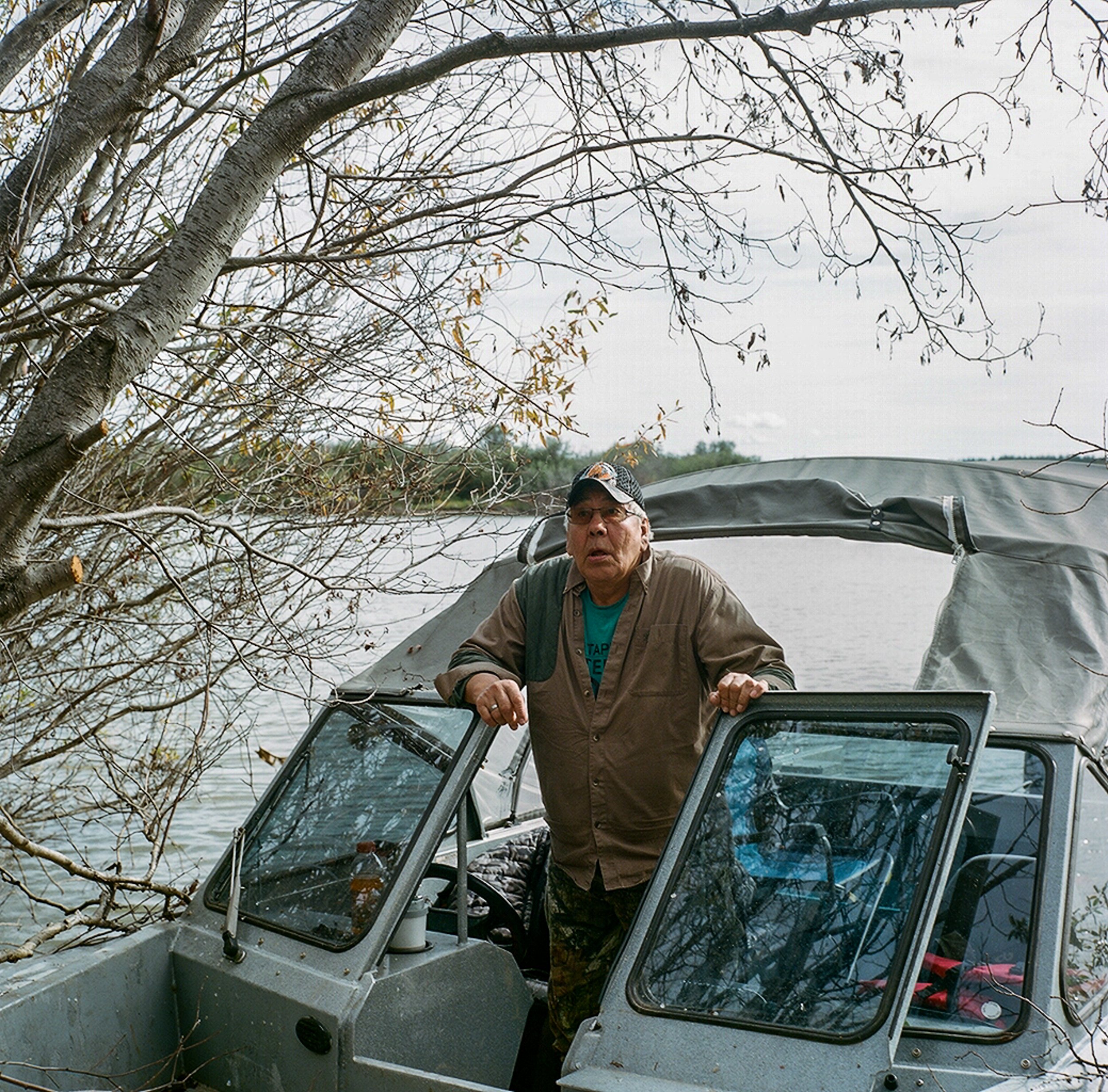 Mikisew Cree First Nation elder George Sloan Whiteknife drives a boat on Lake Athabasca with youth. Whiteknife grew up hunting and fishing with his father, and has for decades noticed changes to the fish and water levels living downstream from the oi