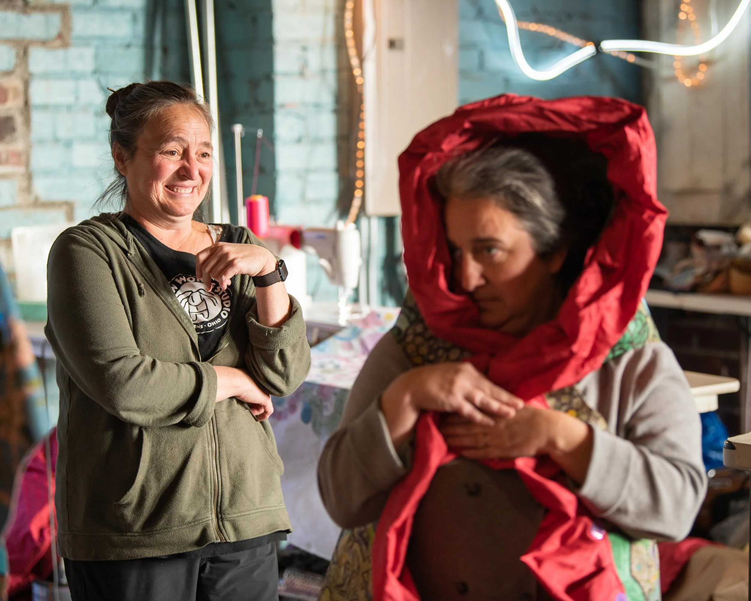 Patty Mitchell (left) has Maureen Wagner (right) try on a costume during preparations for the Honey for the Heart parade in Athens, Ohio, Wednesday, October 23, 2019. The costume uses fabric painted and decorated by volunteers over the three weeks le